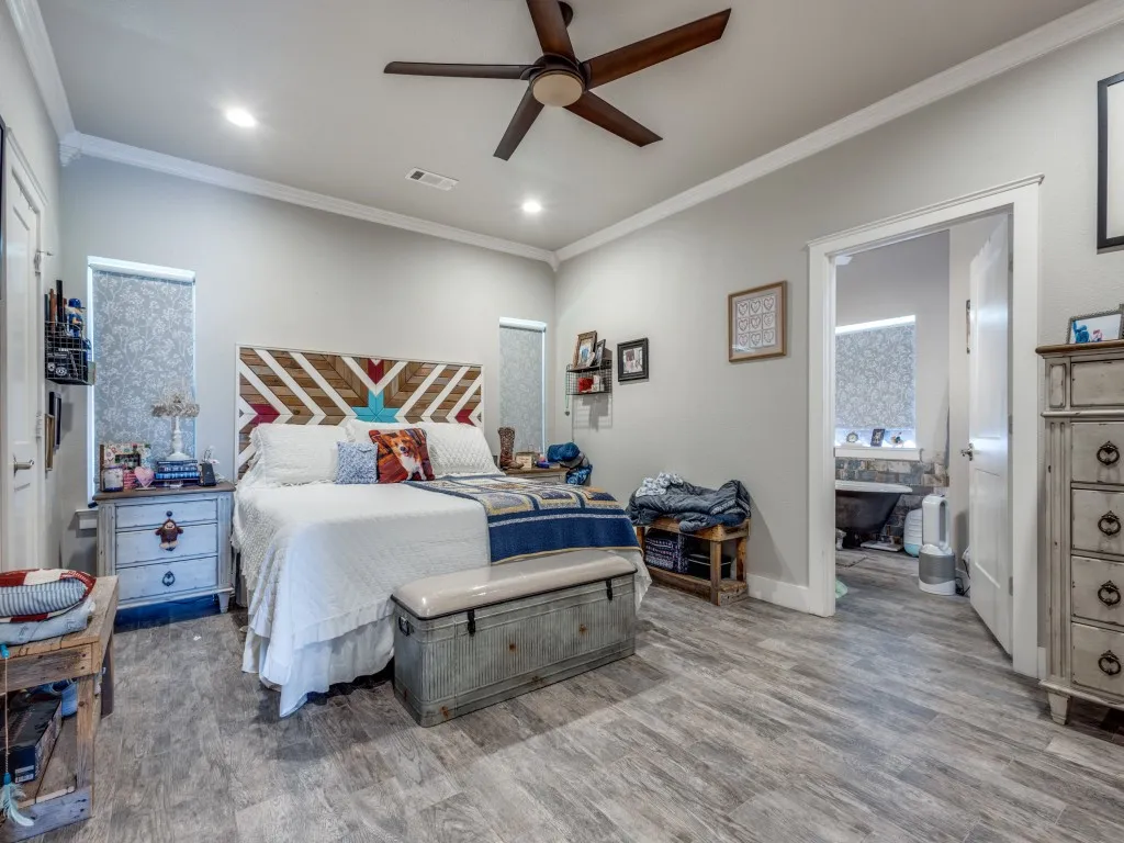 Bedroom featuring crown molding, connected bathroom, ceiling fan, and light wood-type flooring