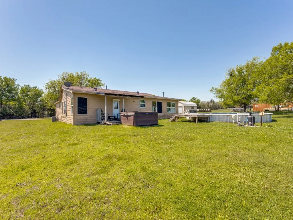 Rear view of house featuring a hot tub and yard