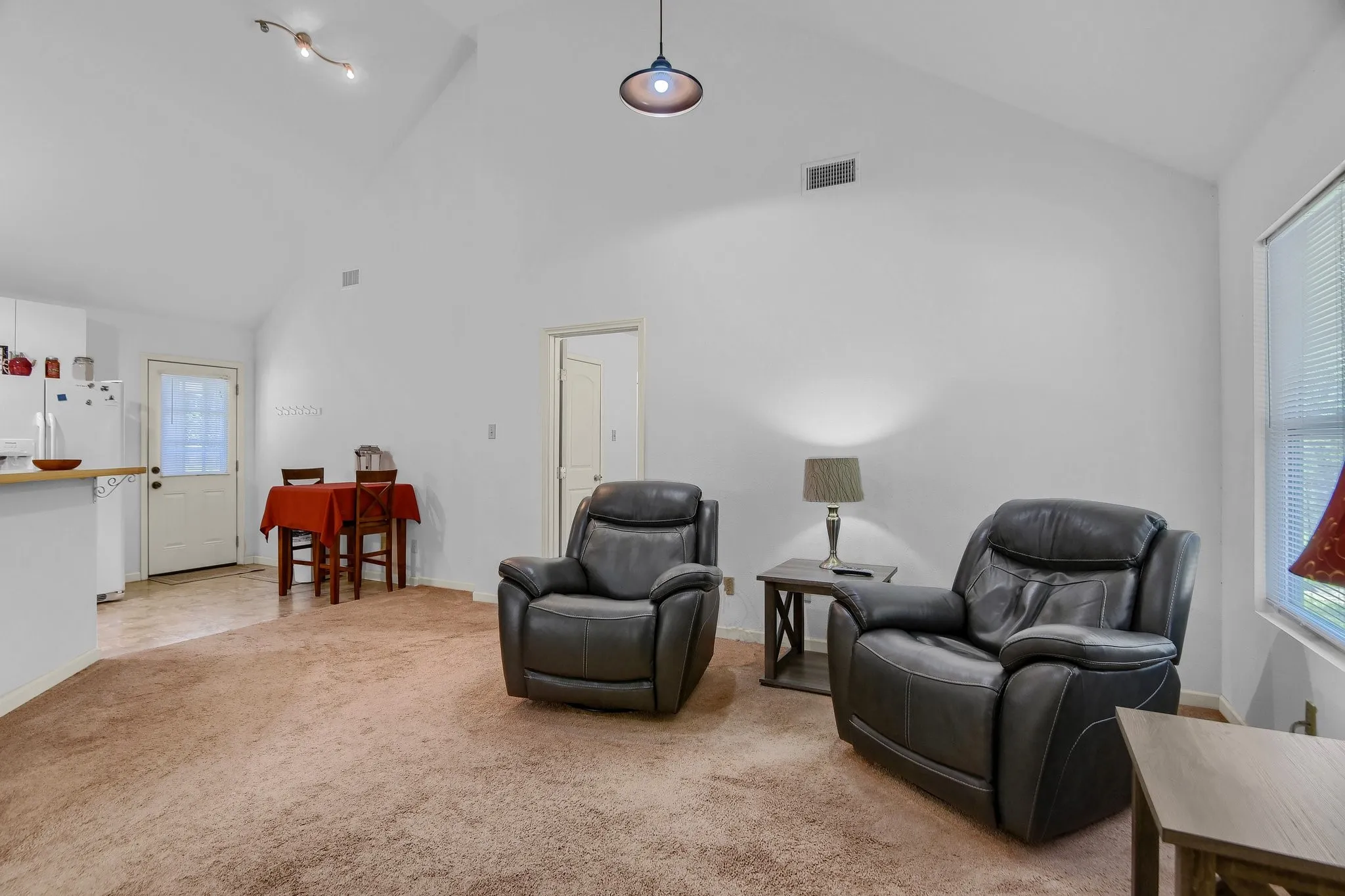 Living area featuring light carpet, plenty of natural light, and high vaulted ceiling