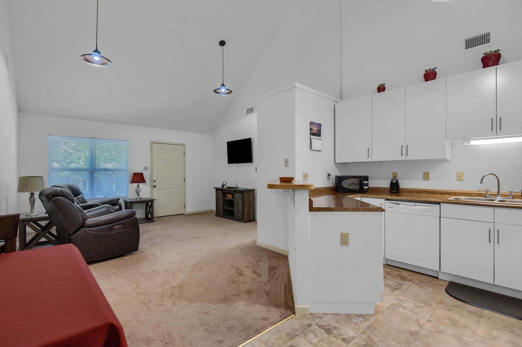 Kitchen with white cabinetry, hanging light fixtures, dishwasher, and sink