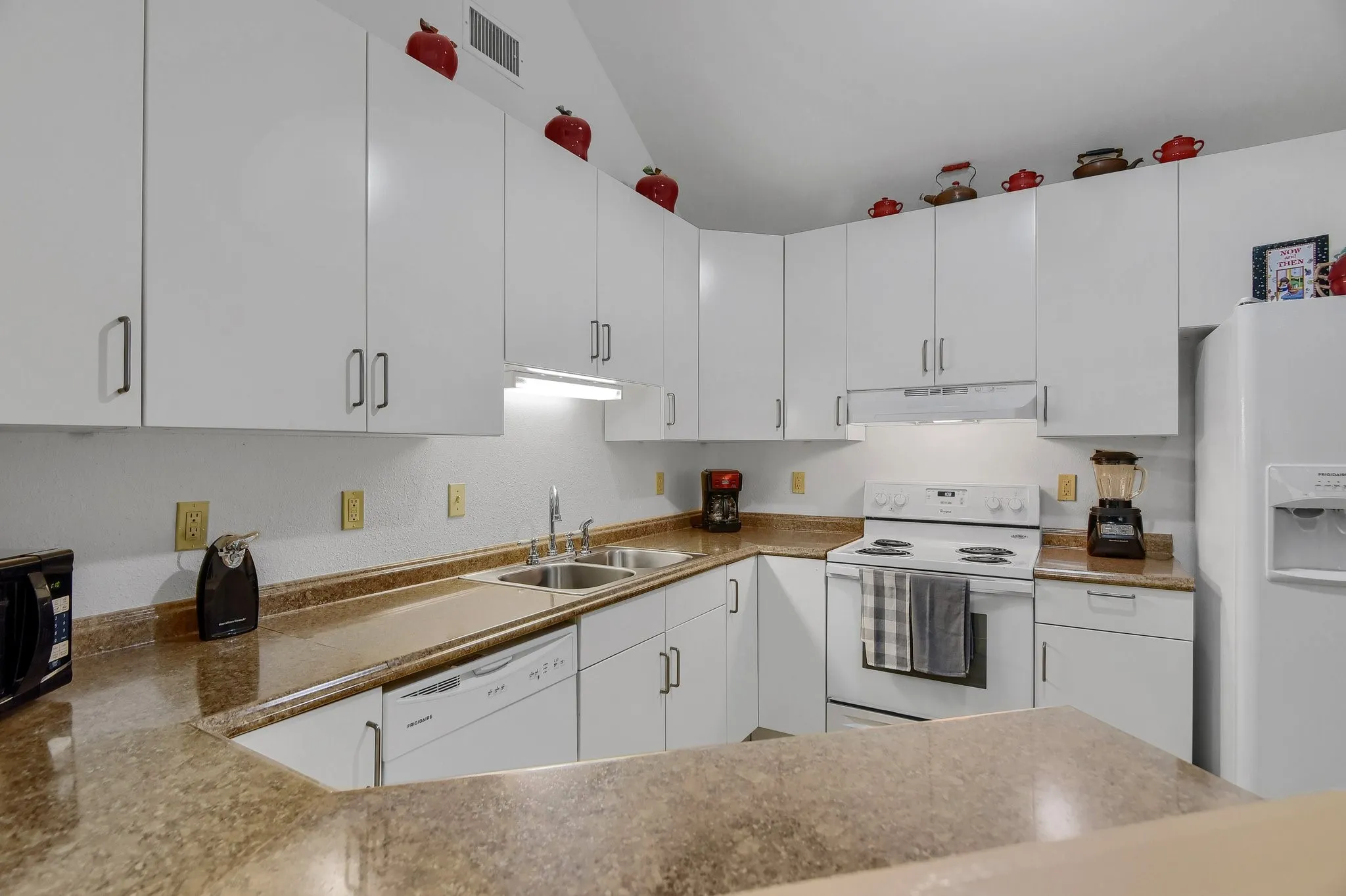 Kitchen with white appliances, sink, custom range hood, and white cabinetry