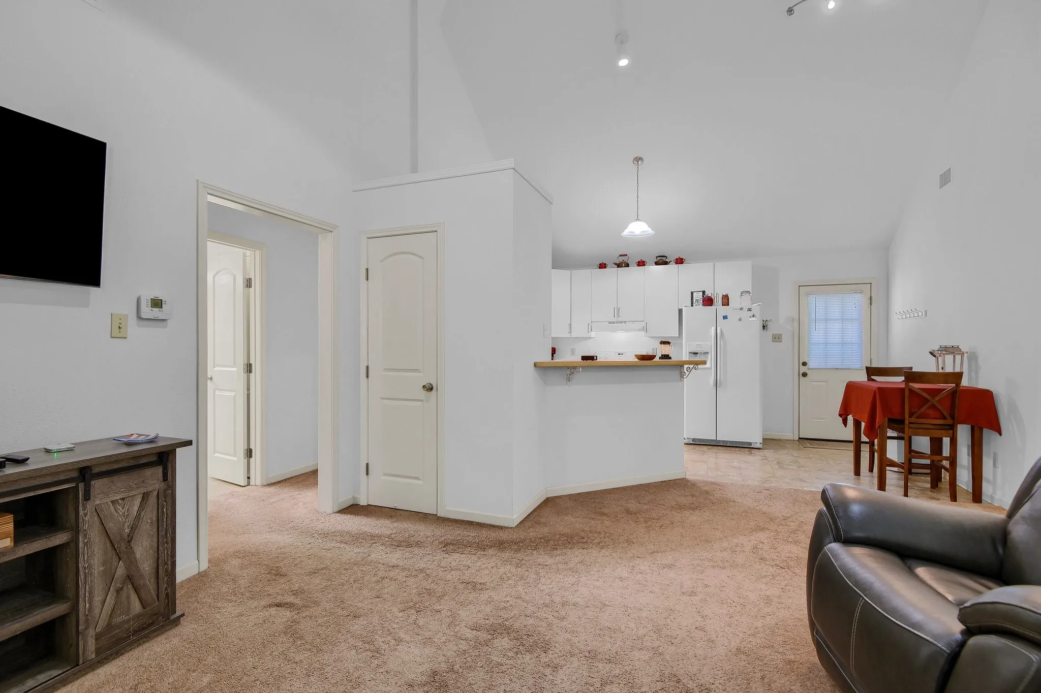 Living room featuring light colored carpet and high vaulted ceiling