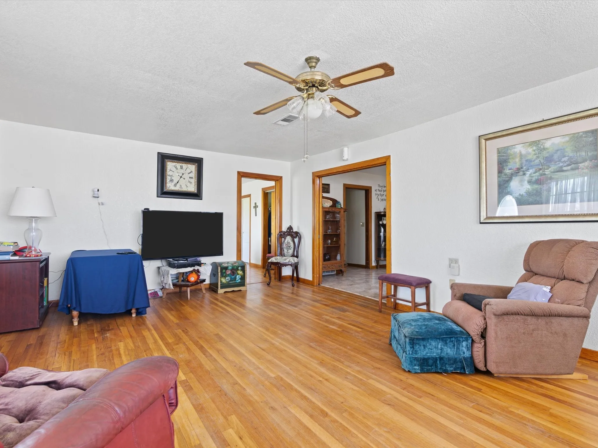 Living room featuring a textured ceiling, ceiling fan, and light wood-type flooring
