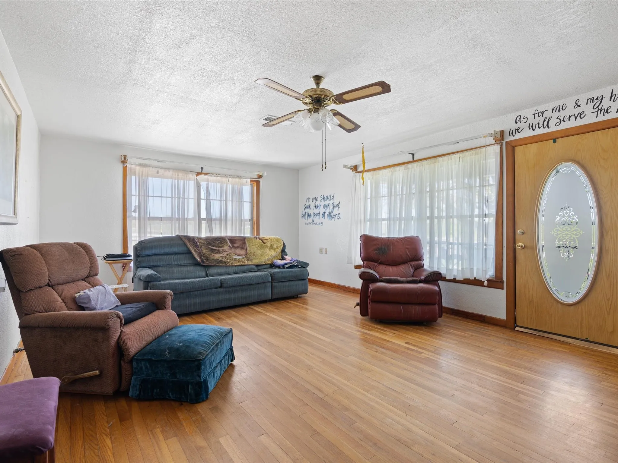 Living room featuring light hardwood / wood-style flooring, ceiling fan, and a textured ceiling