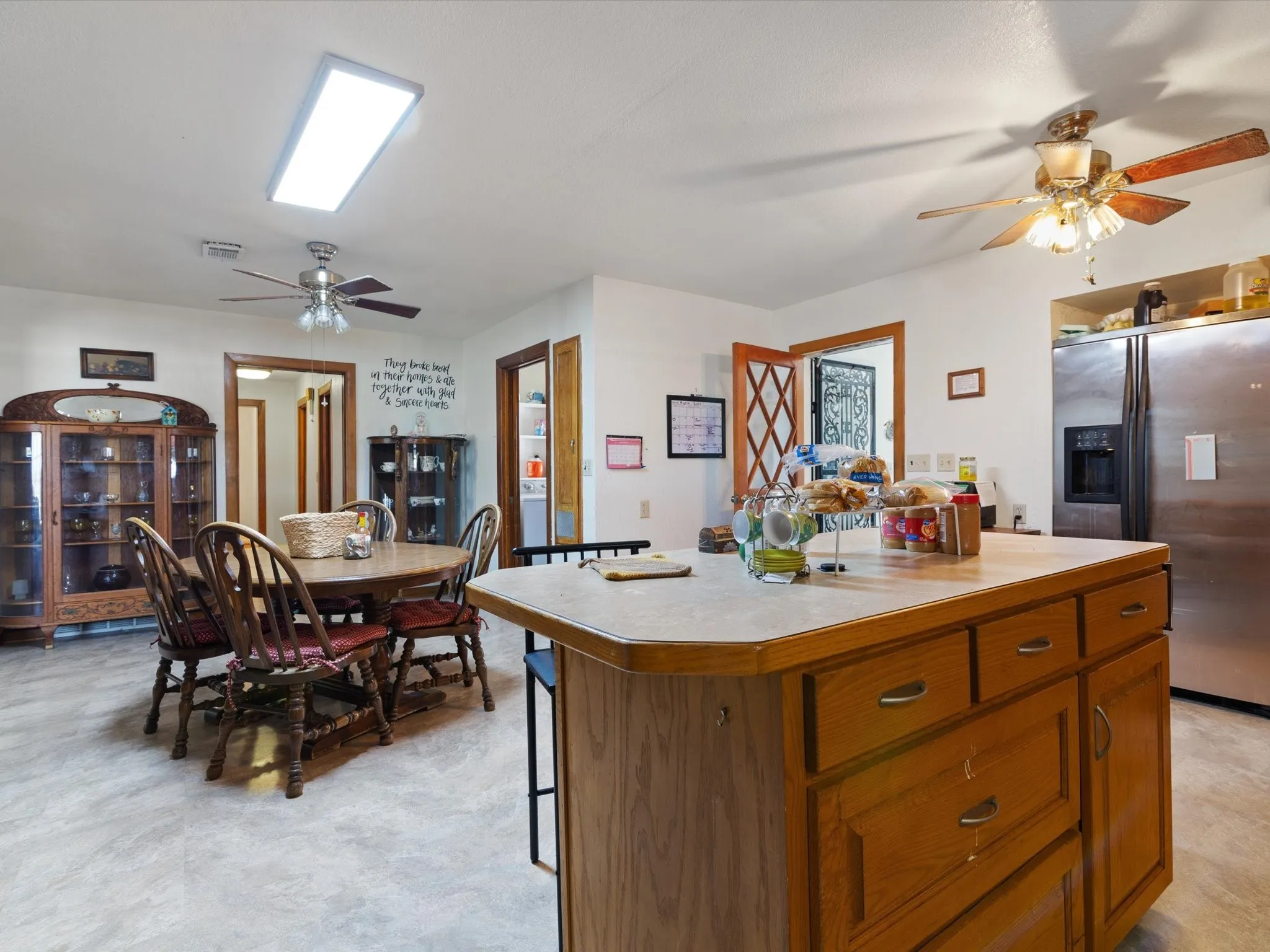 Kitchen with stainless steel fridge, ceiling fan, a breakfast bar area, and a center island