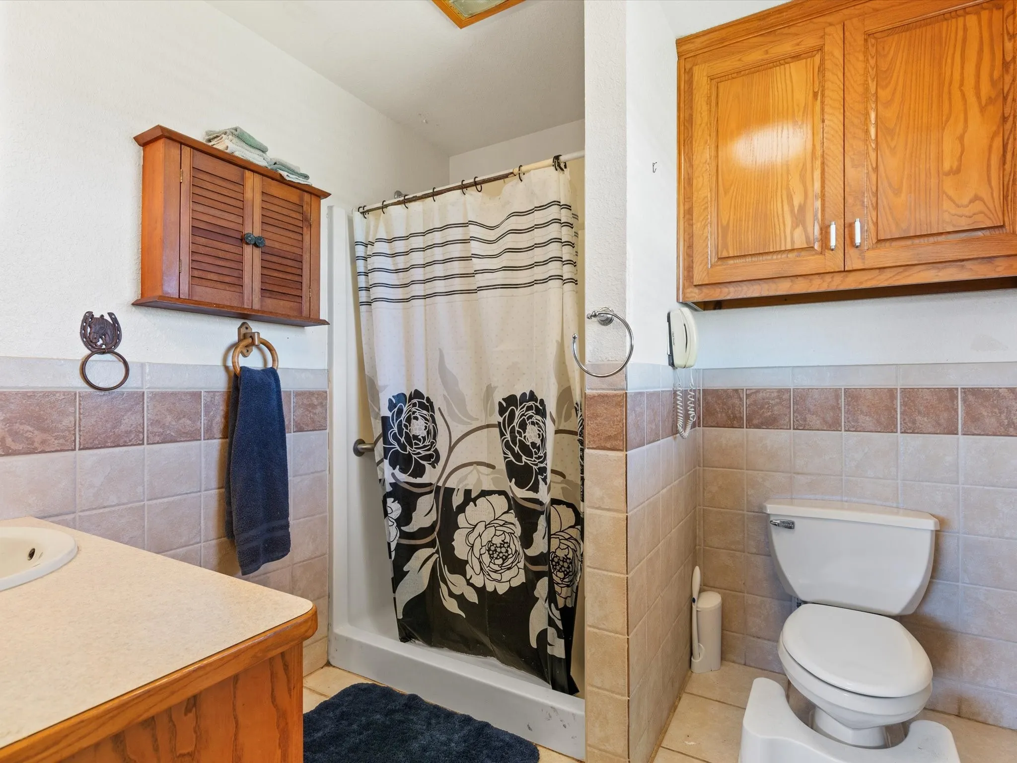 Bathroom featuring walk in shower, tile walls, tile floors, toilet, and vanity