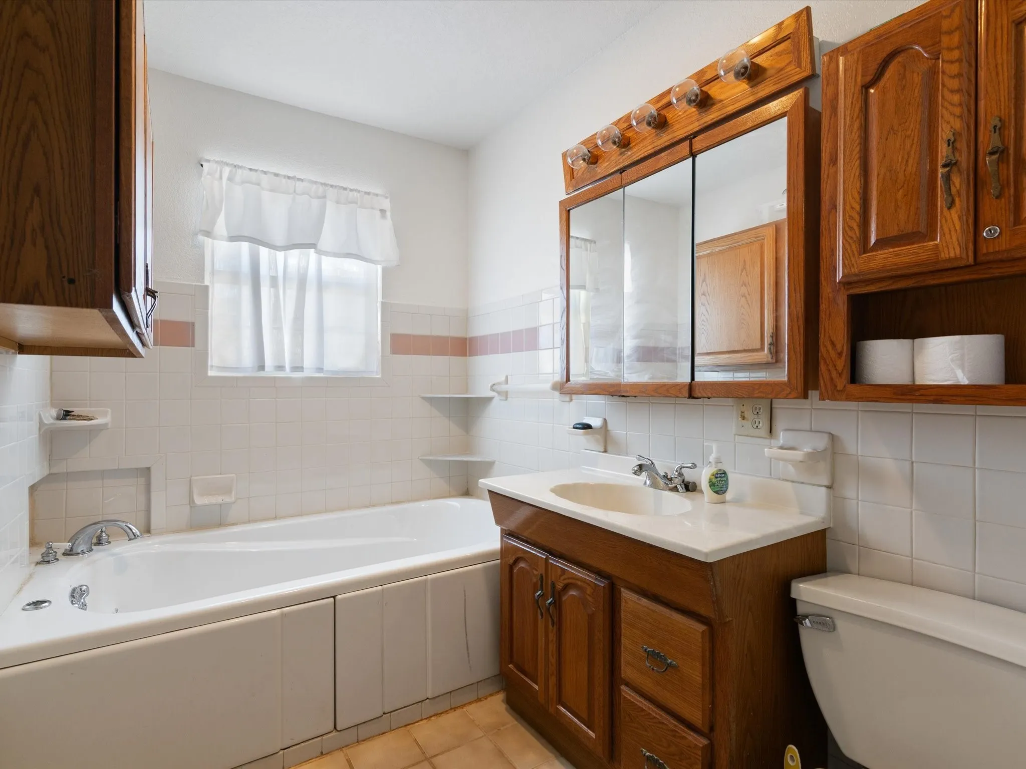 Bathroom featuring tile flooring, a tub, toilet, and tile walls