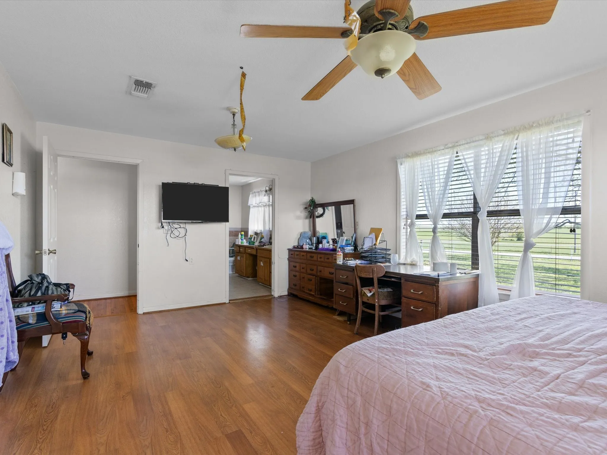 Bedroom with ceiling fan, ensuite bathroom, and dark wood-type flooring