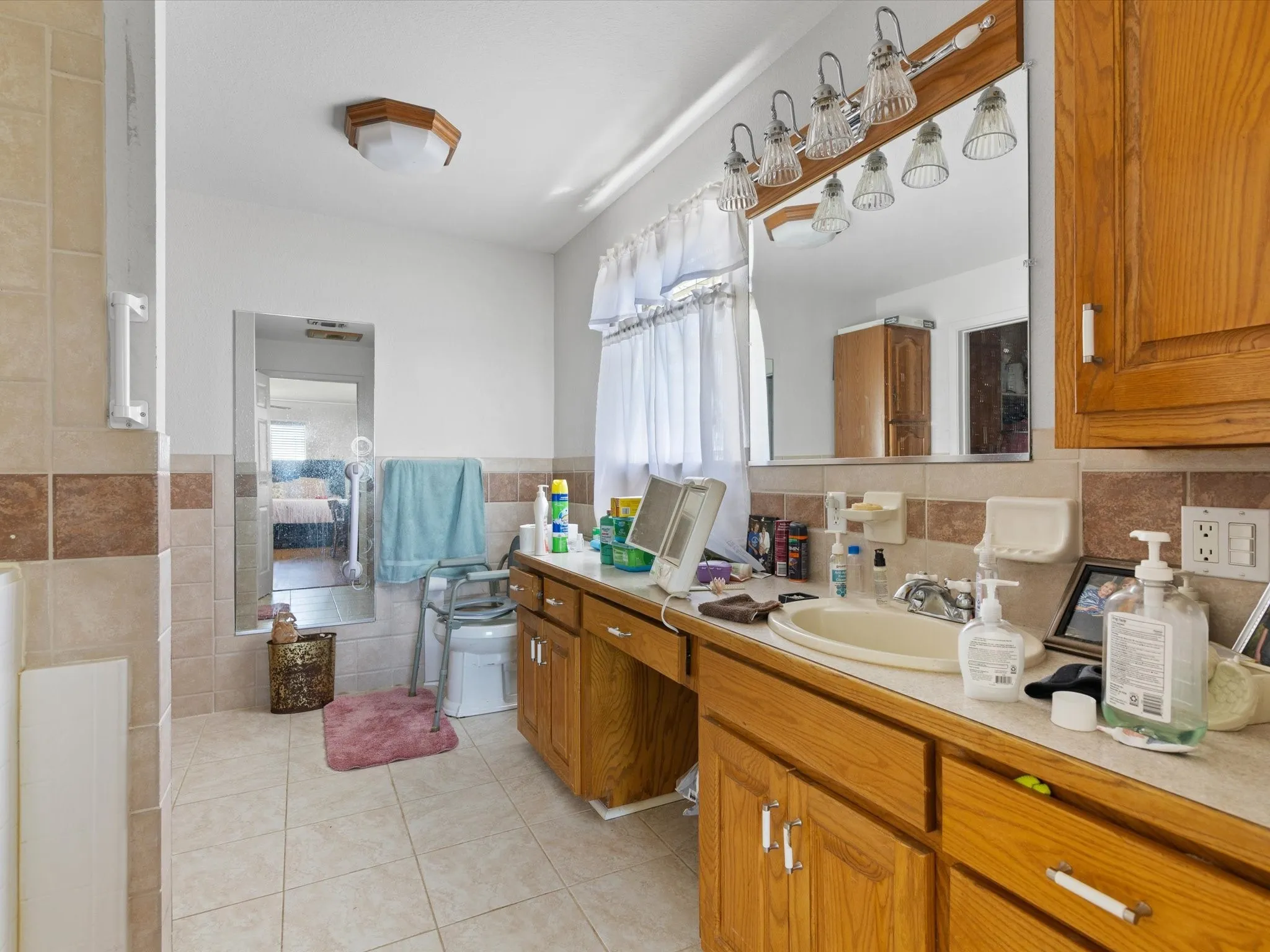 Bathroom featuring tile flooring, vanity with extensive cabinet space, tasteful backsplash, and tile walls