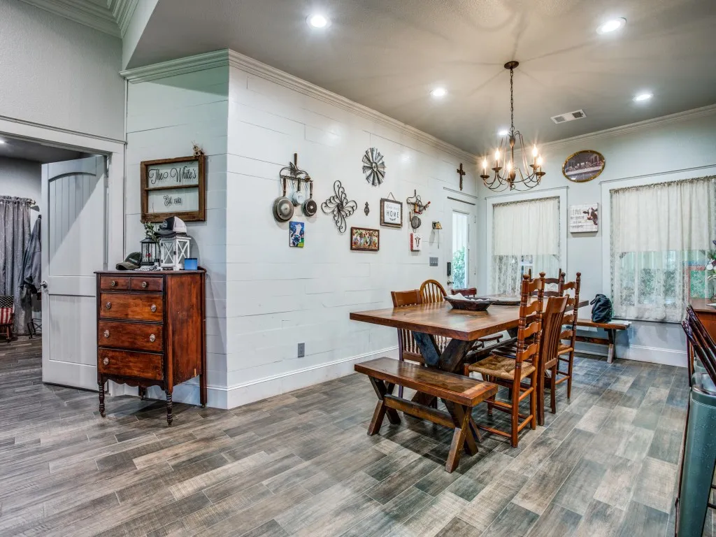 Main house dining space featuring dark wood-type flooring, crown molding, and an inviting chandelier