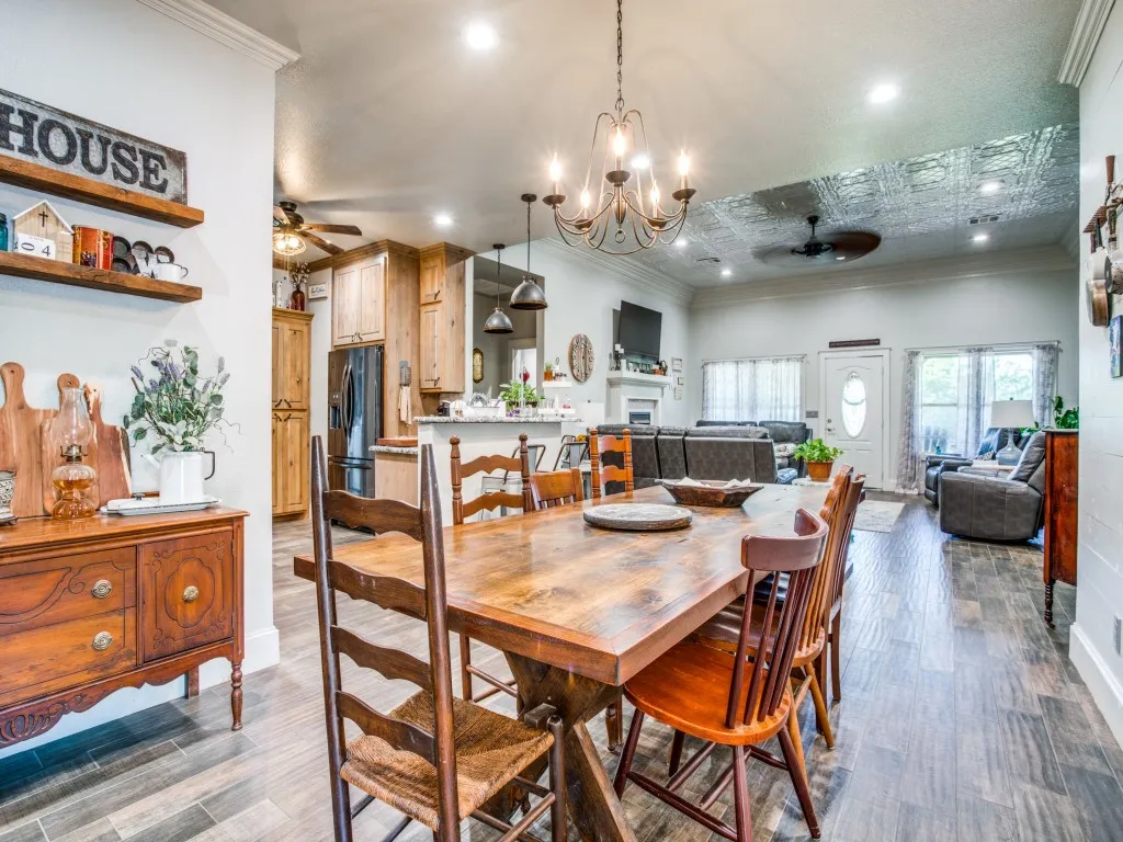Main house dining room featuring ceiling fan with notable chandelier, crown molding, dark wood-type flooring, and a textured ceiling