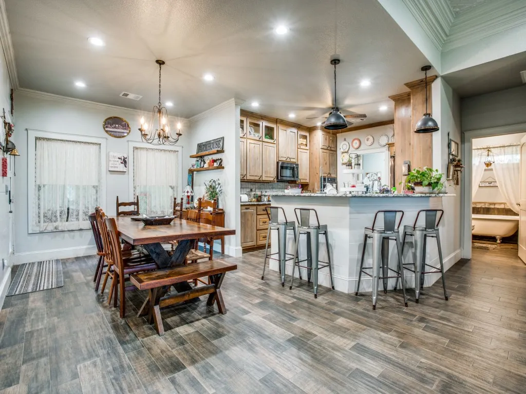 Main house dining area with dark hardwood / wood-style flooring, ceiling fan with notable chandelier, and crown molding