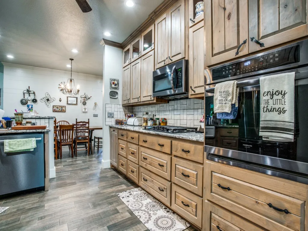 Main house kitchen with appliances with stainless steel finishes, dark hardwood / wood-style floors, tasteful backsplash, pendant lighting, and a chandelier