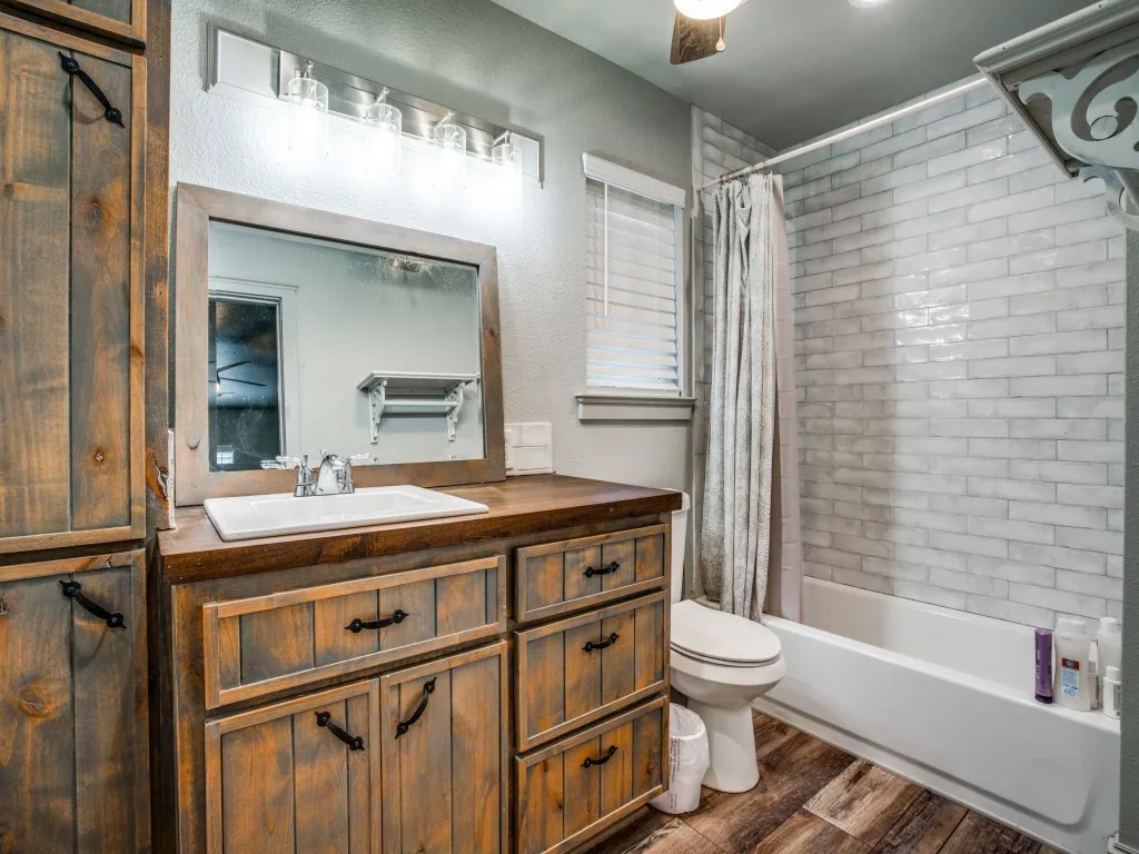 Second living quarters full bathroom featuring shower / tub combo, vanity, hardwood / wood-style flooring, toilet, and ceiling fan