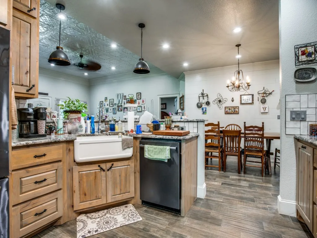 Main house kitchen featuring decorative light fixtures, dishwasher, ornamental molding, and dark hardwood / wood-style floors