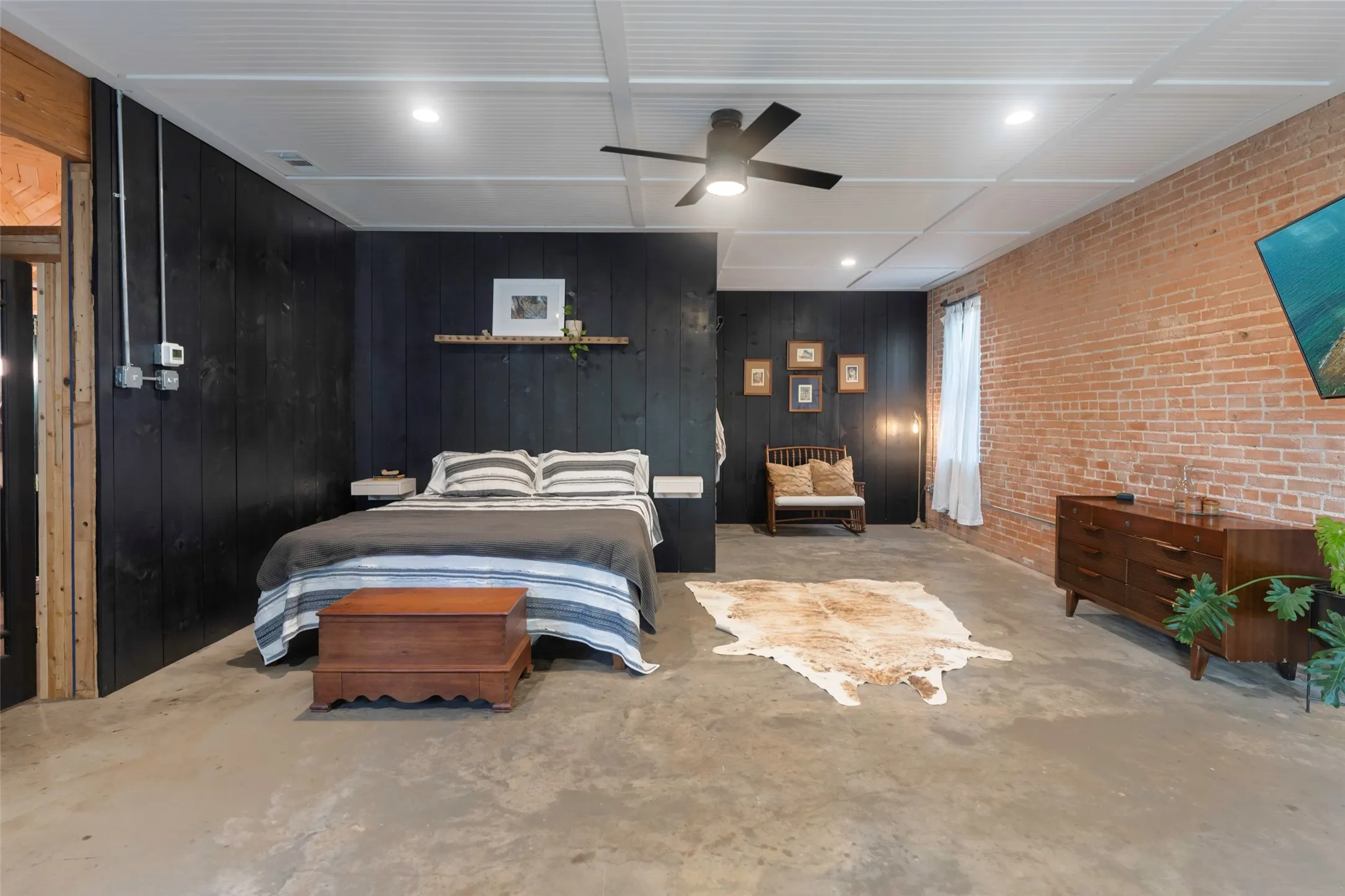 Bedroom featuring ceiling fan, brick wall, and wooden walls
