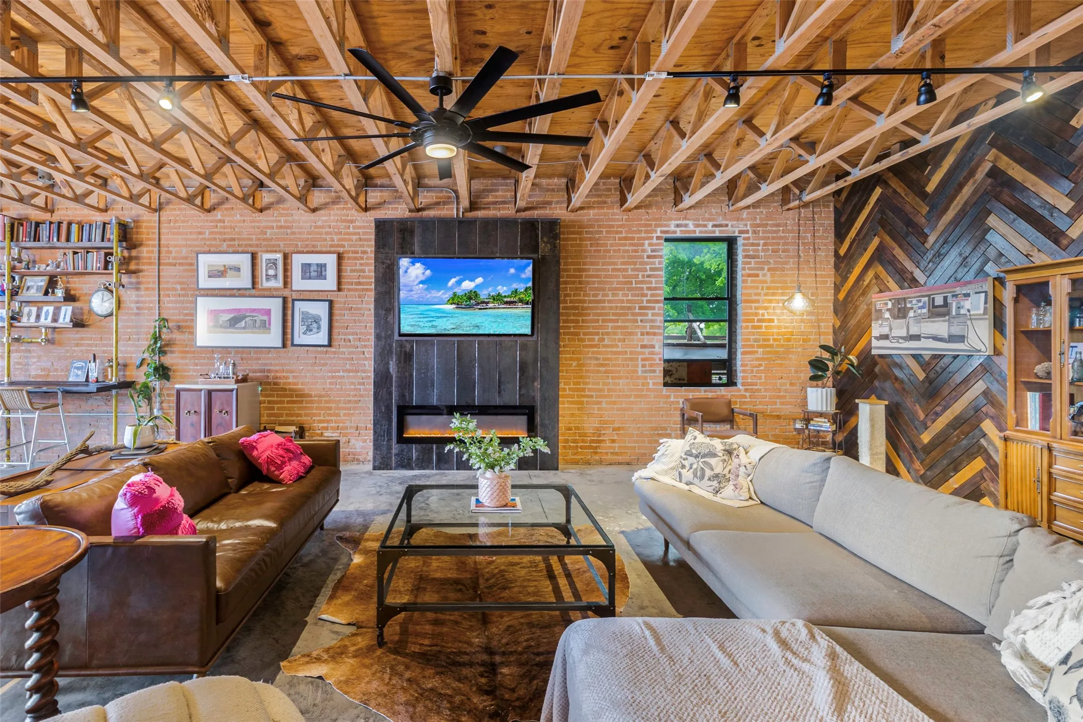 Living room with brick wall, wood ceiling, ceiling fan, and beamed ceiling
