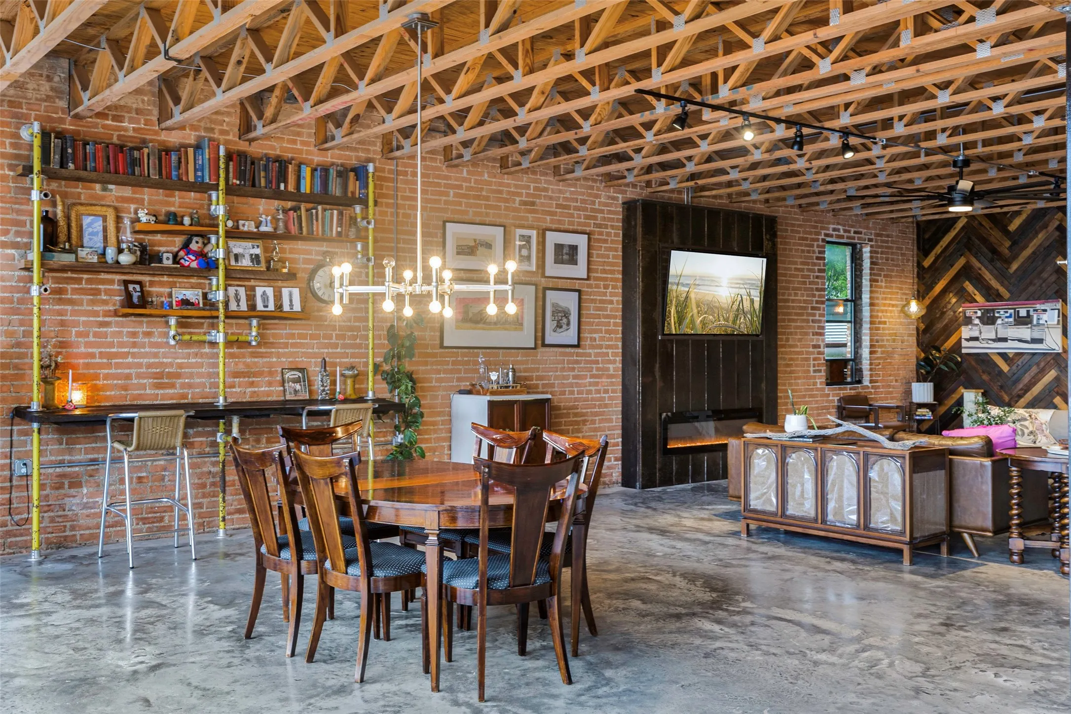 Dining space featuring ceiling fan with notable chandelier and brick wall