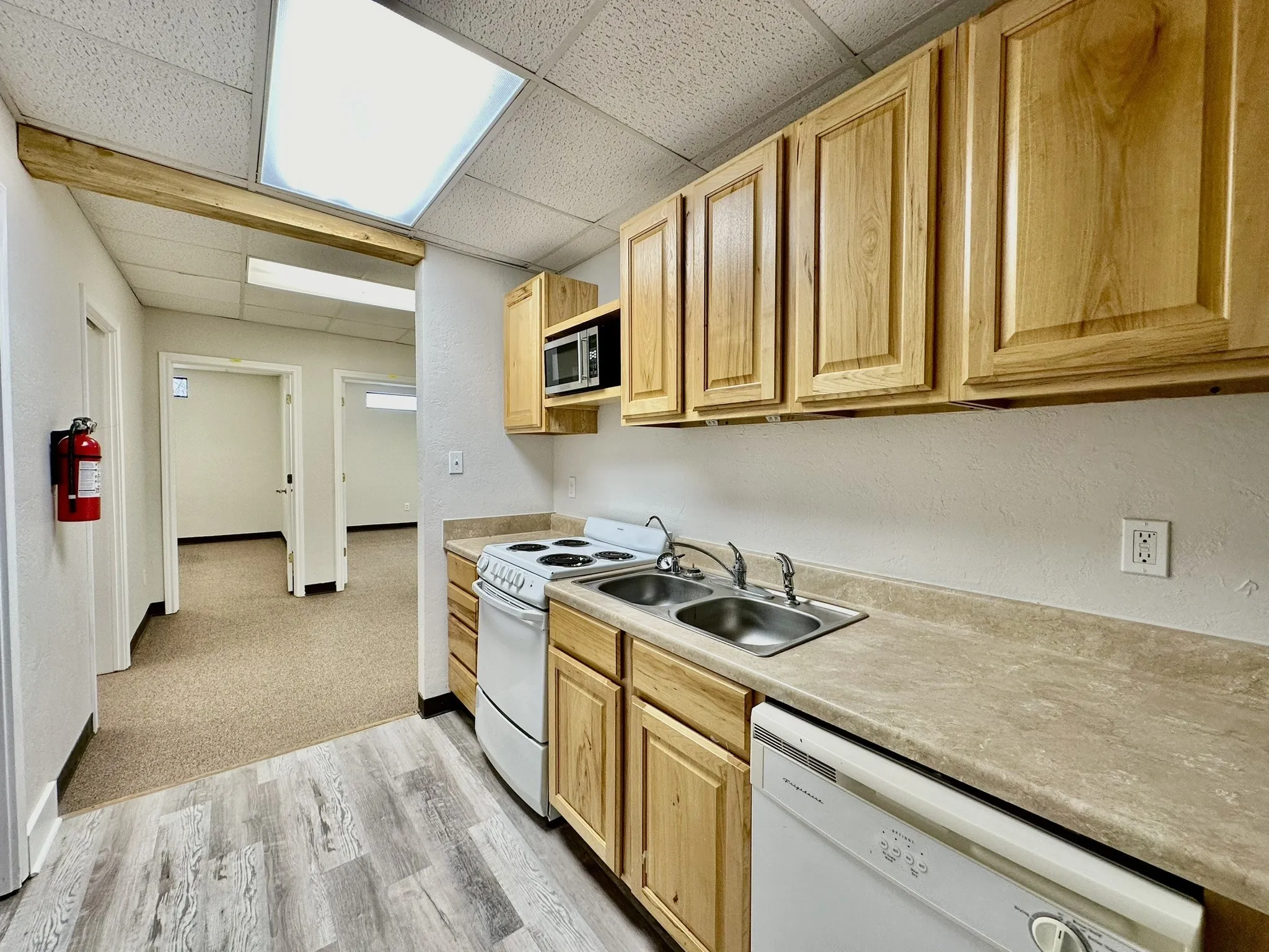 Kitchen featuring white appliances, light hardwood / wood-style floors, sink, and a paneled ceiling