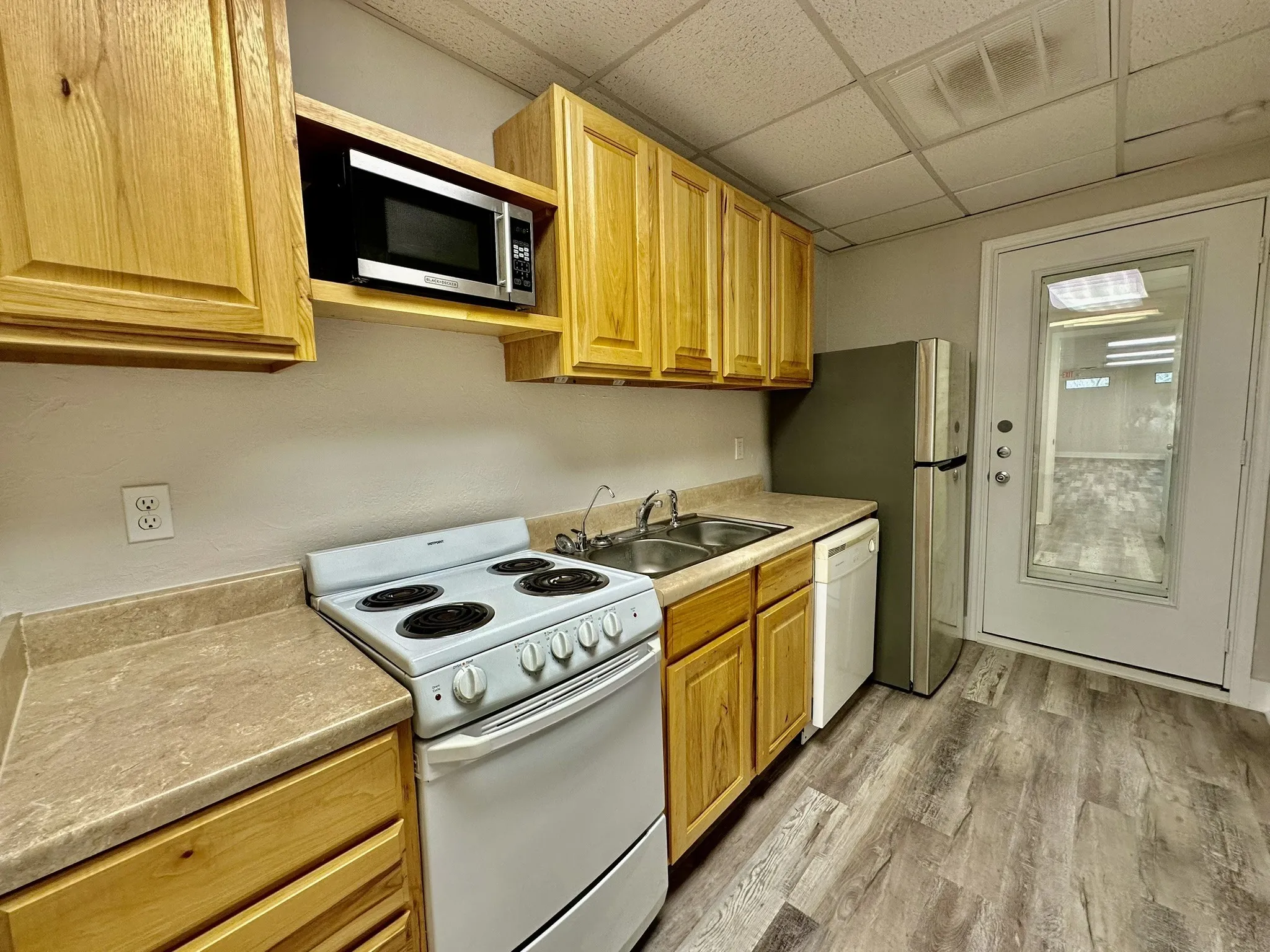 Kitchen featuring sink, light hardwood / wood-style floors, white appliances, and a paneled ceiling