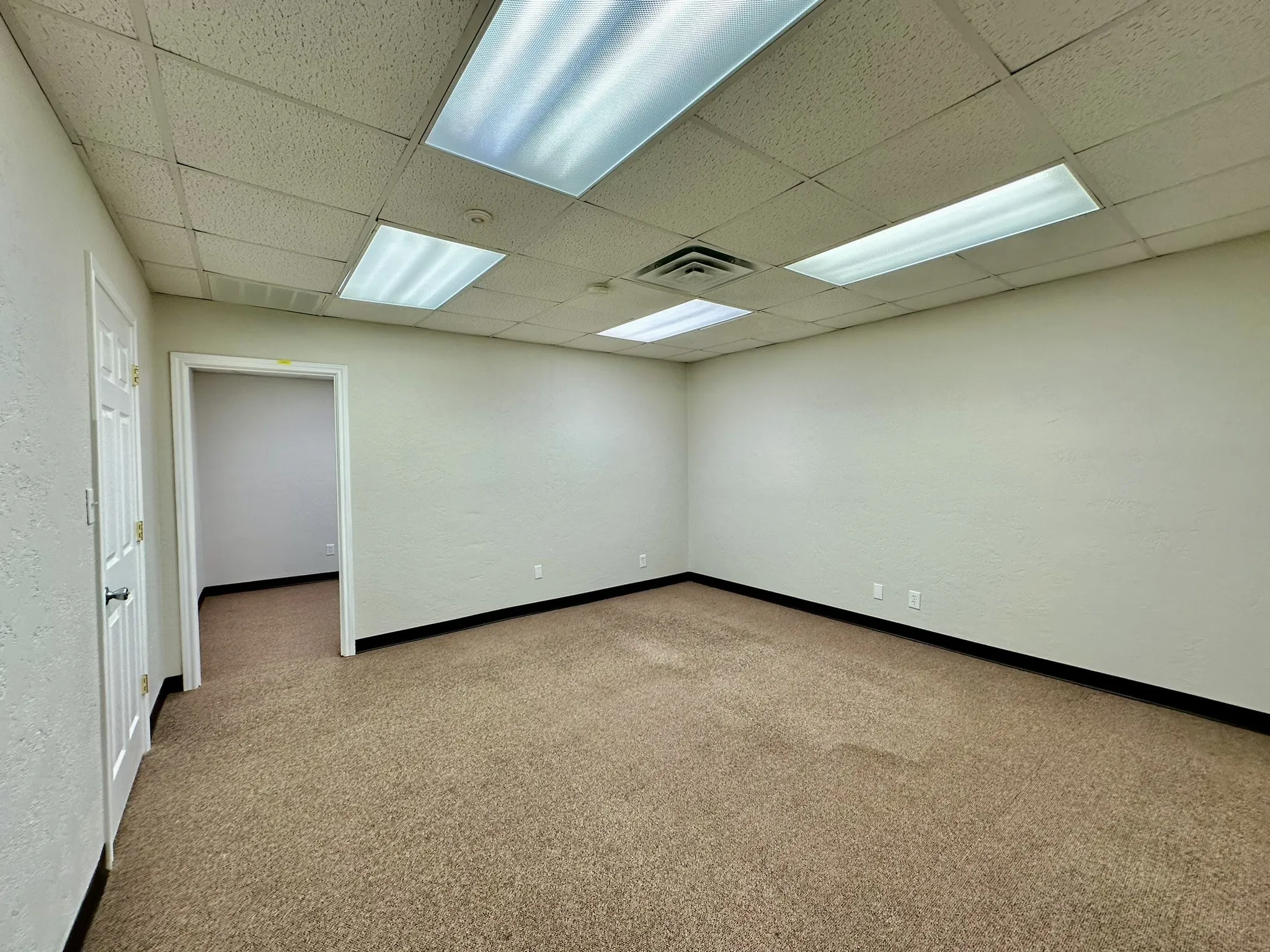 Empty room with a drop ceiling and carpet