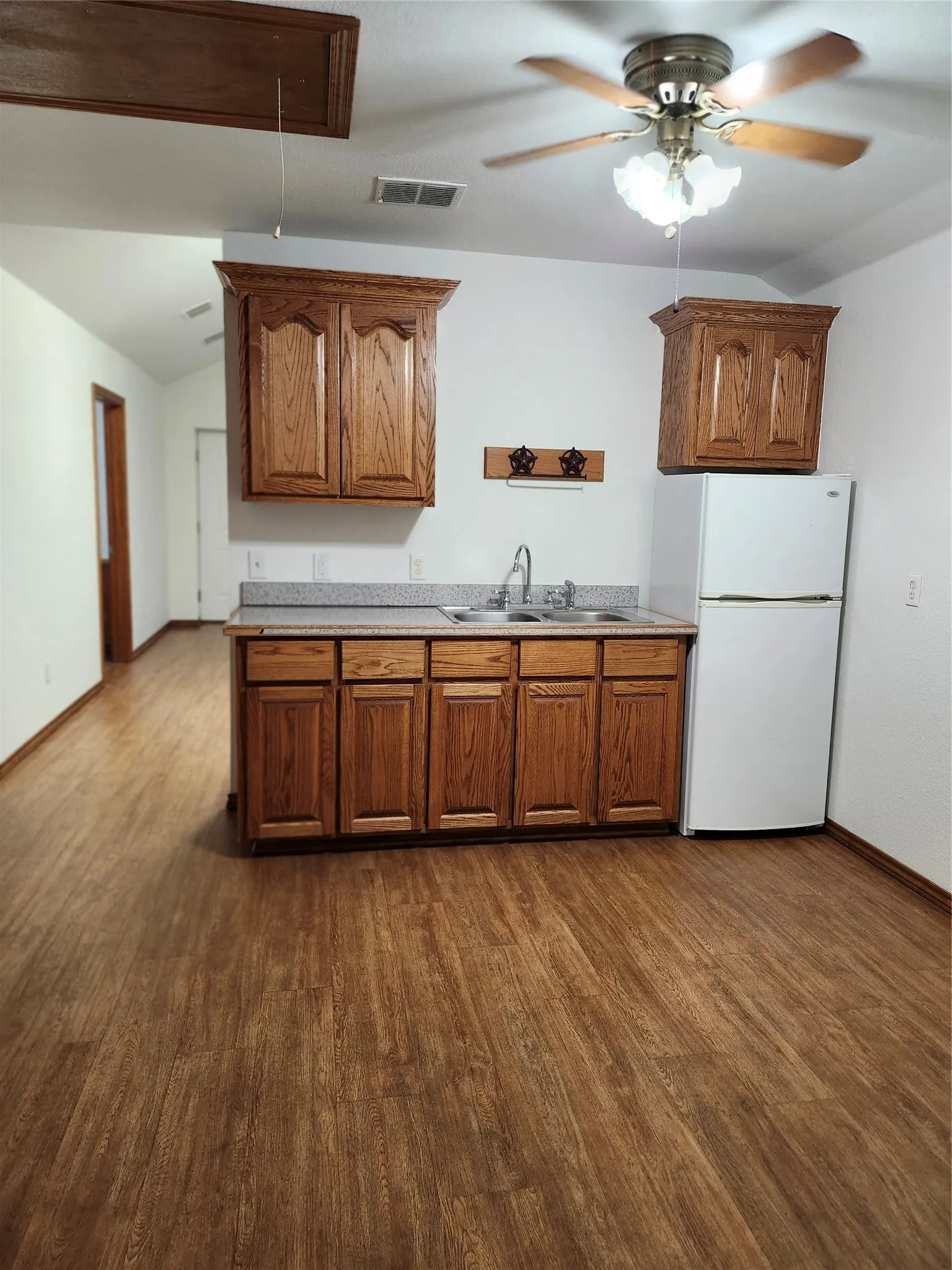 Kitchen with refrigerator, sink, hardwood / wood-style flooring, and ceiling fan