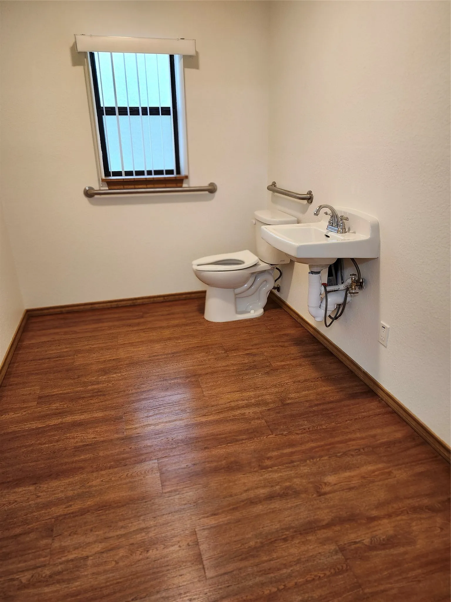 Bathroom featuring wood-type flooring, sink, and toilet