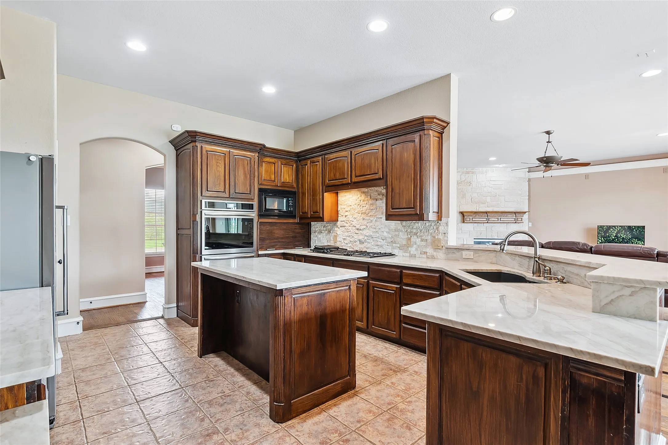 Kitchen with stainless steel appliances, ceiling fan, tasteful backsplash, a center island, and sink