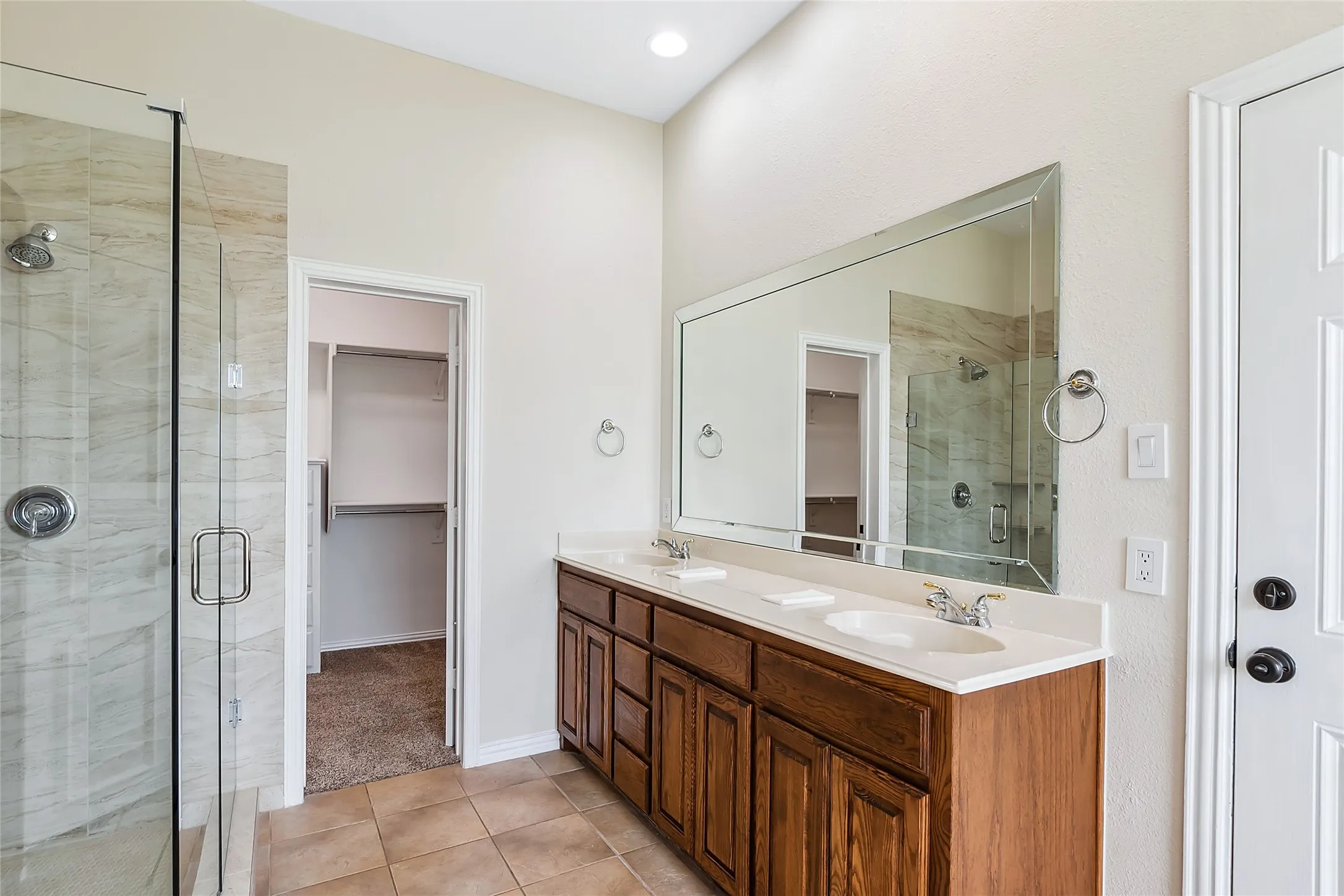 Bathroom with dual vanity, an enclosed shower, and tile flooring