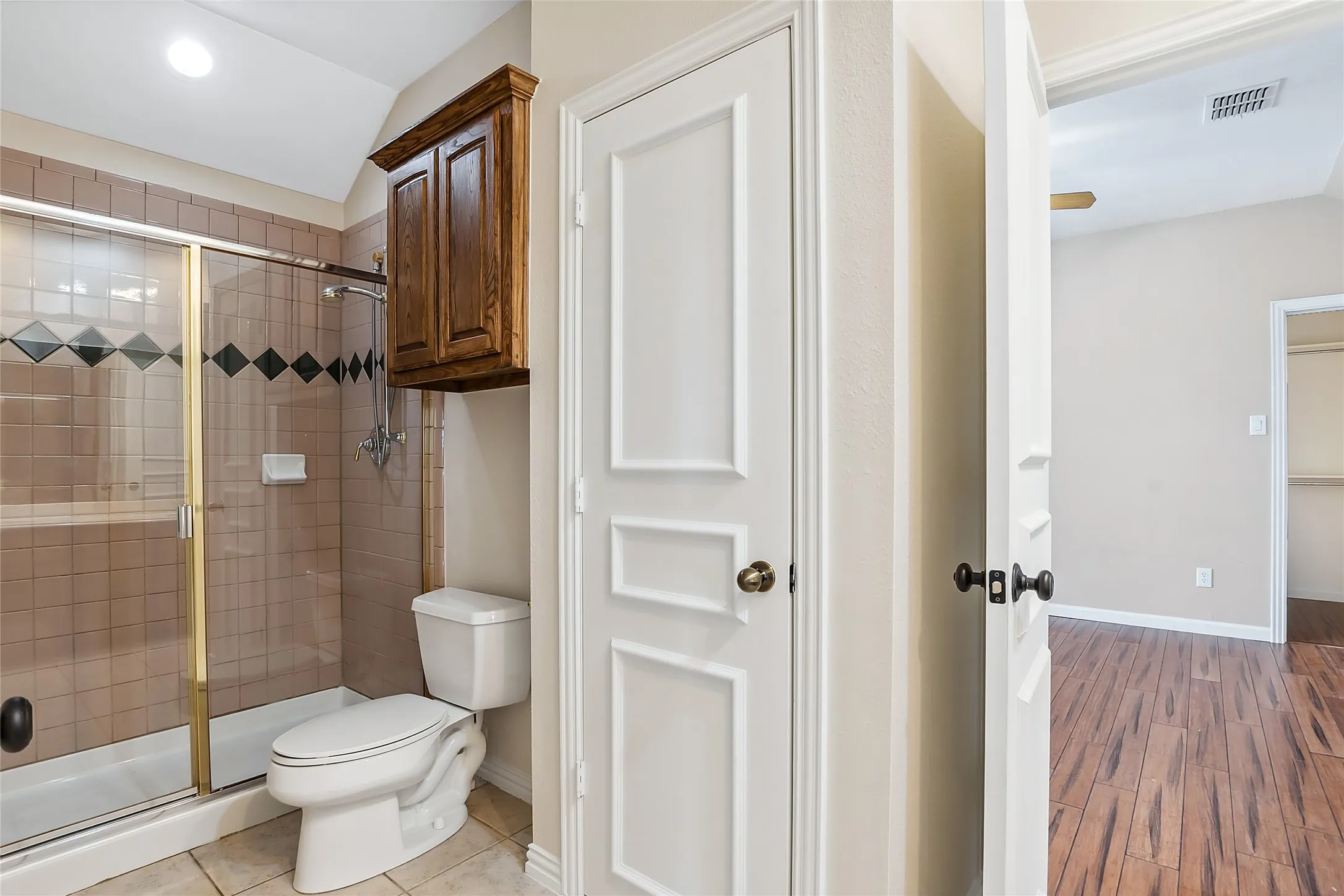 Bathroom featuring an enclosed shower, hardwood / wood-style flooring, and toilet