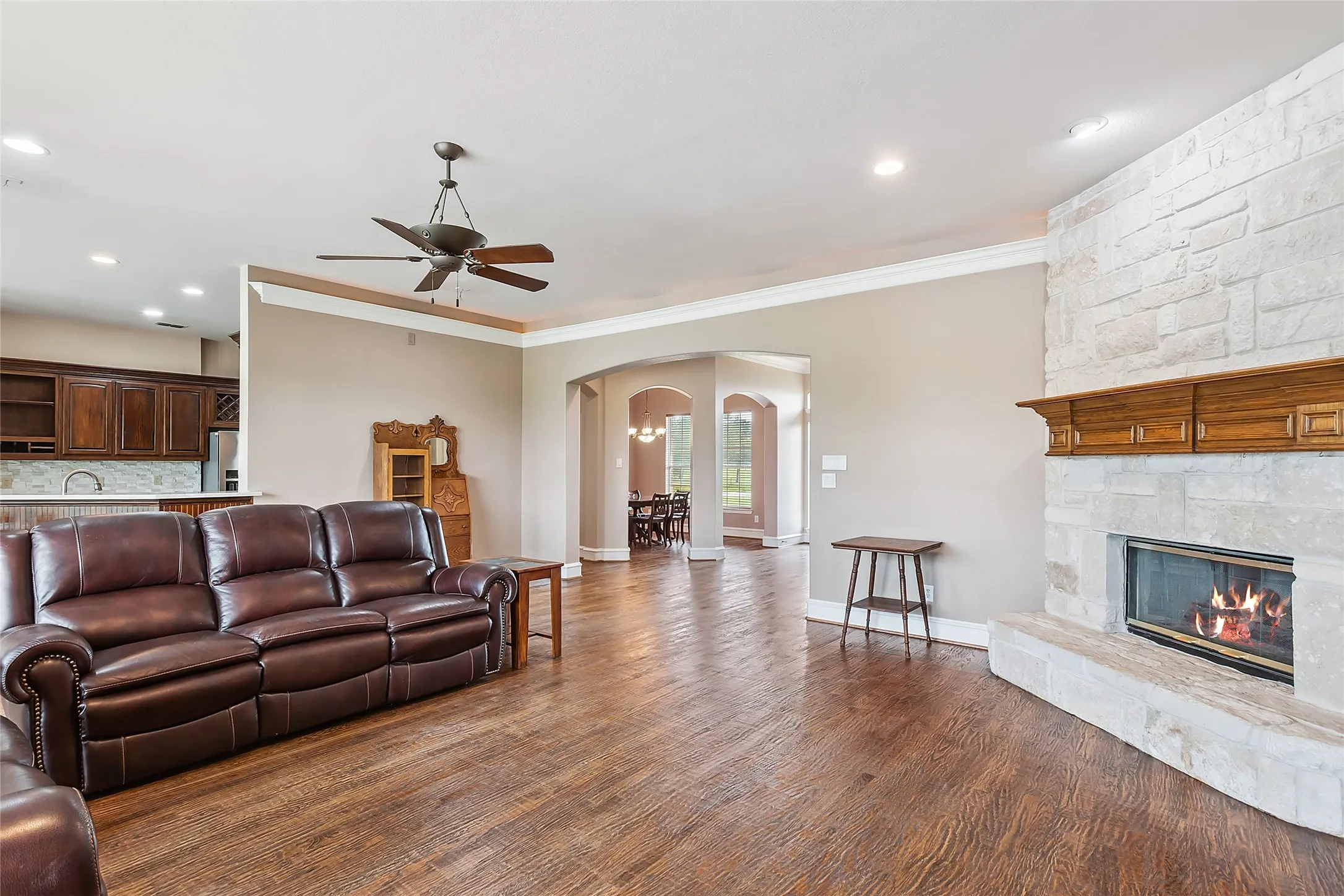 Living room with ceiling fan, a fireplace, dark hardwood / wood-style flooring, sink, and ornamental molding