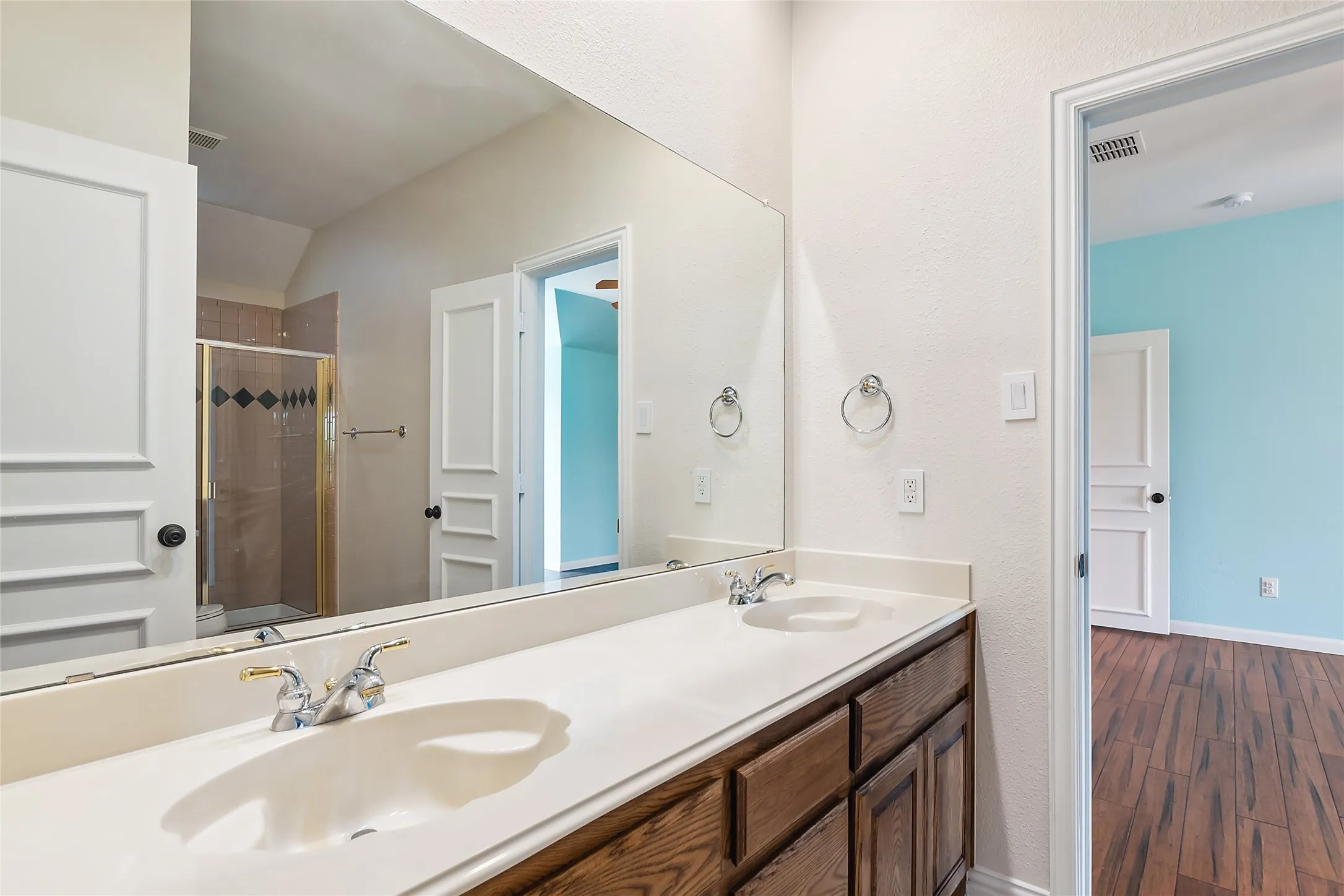Bathroom featuring hardwood / wood-style floors, a shower with door, large vanity, and dual sinks