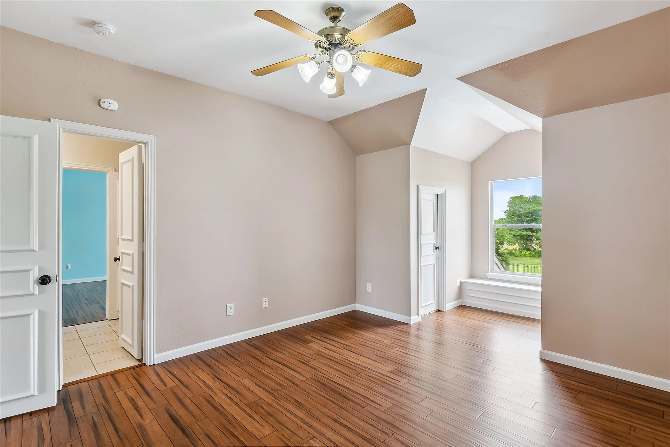 Empty room featuring ceiling fan, light tile floors, and lofted ceiling