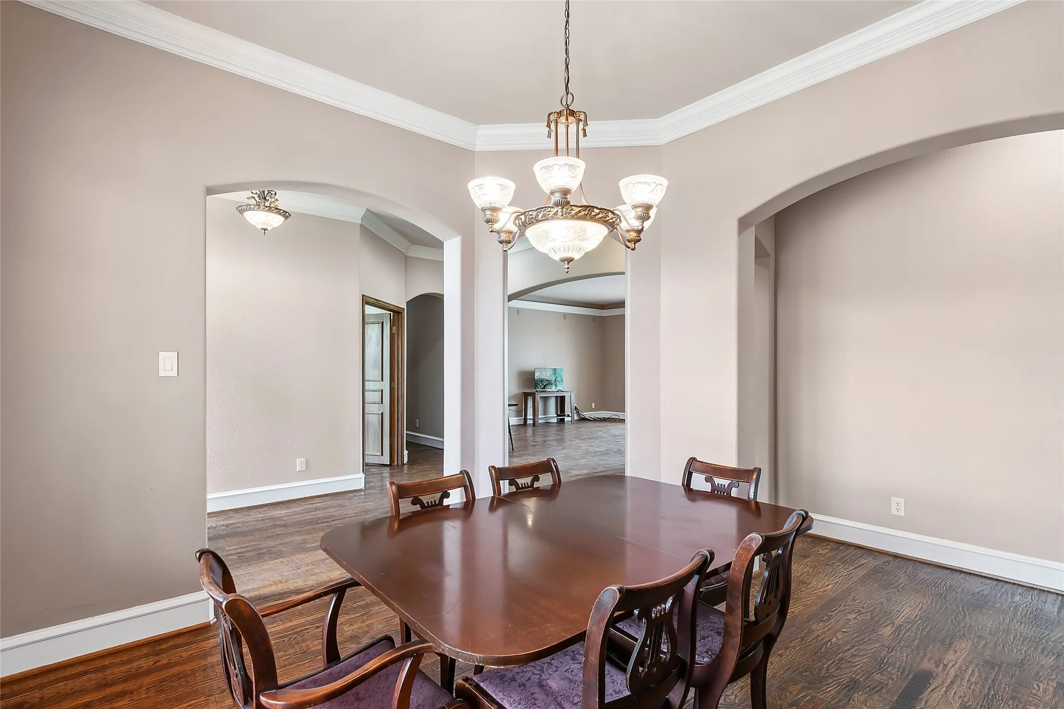 Dining space featuring a notable chandelier, dark hardwood flooring, and ornamental molding