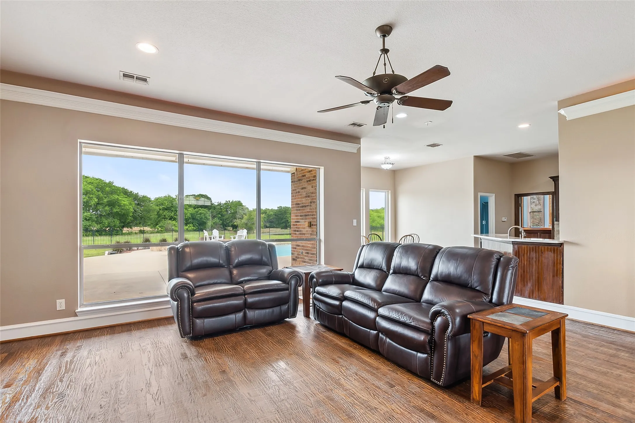 Living room with hardwood floors, ceiling fan, and crown molding