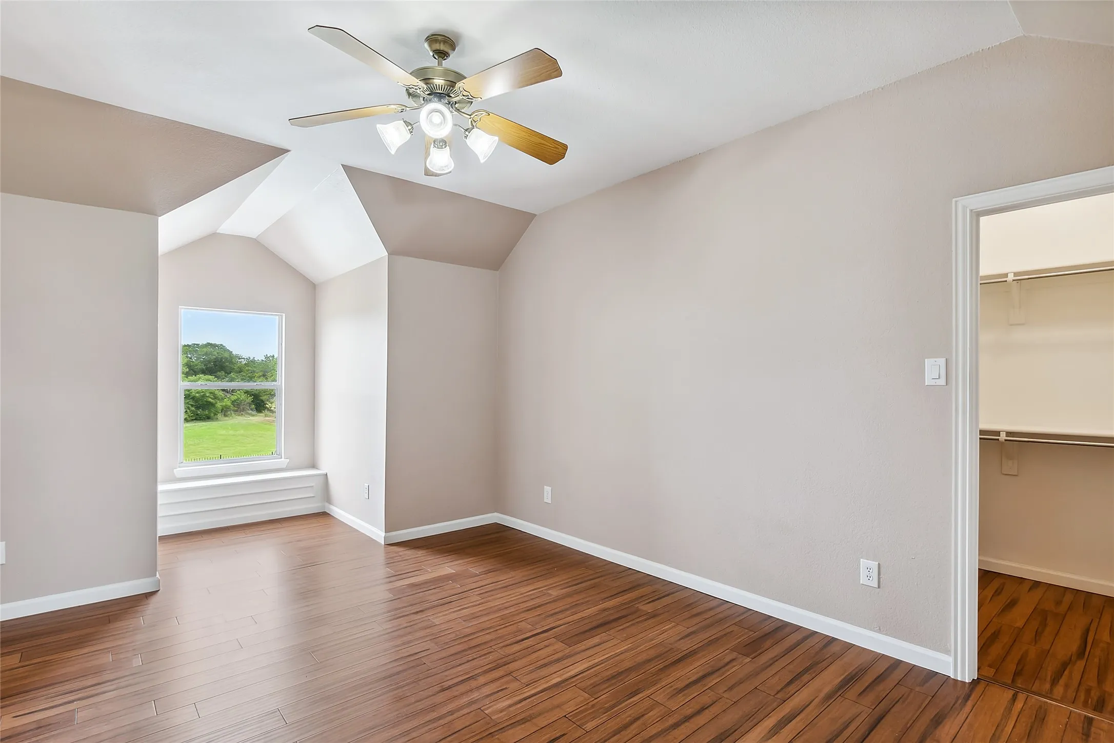 Unfurnished room with hardwood / wood-style flooring, lofted ceiling, and ceiling fan
