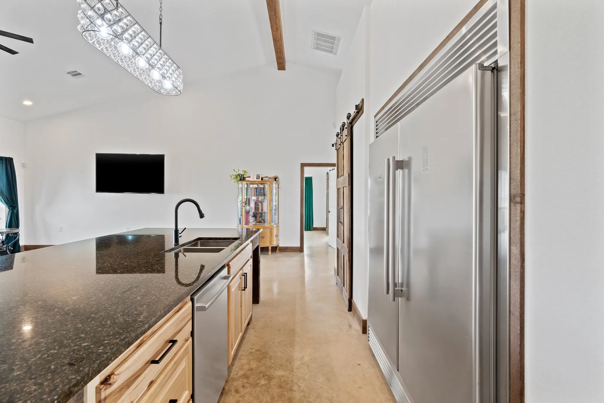 Kitchen featuring dark stone counters, stainless steel appliances, pendant lighting, a barn door, and sink