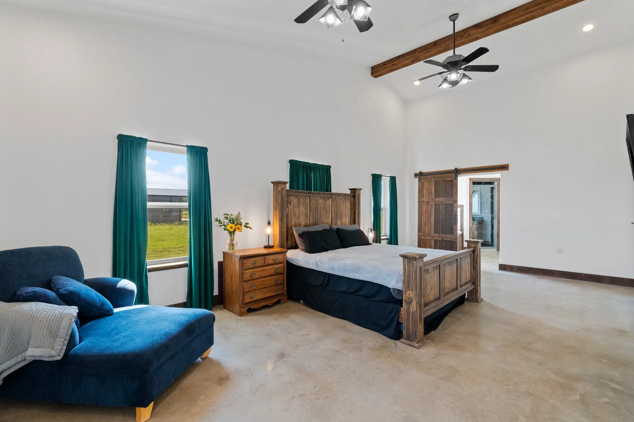 Bedroom with a towering ceiling, ceiling fan, a barn door, and beam ceiling