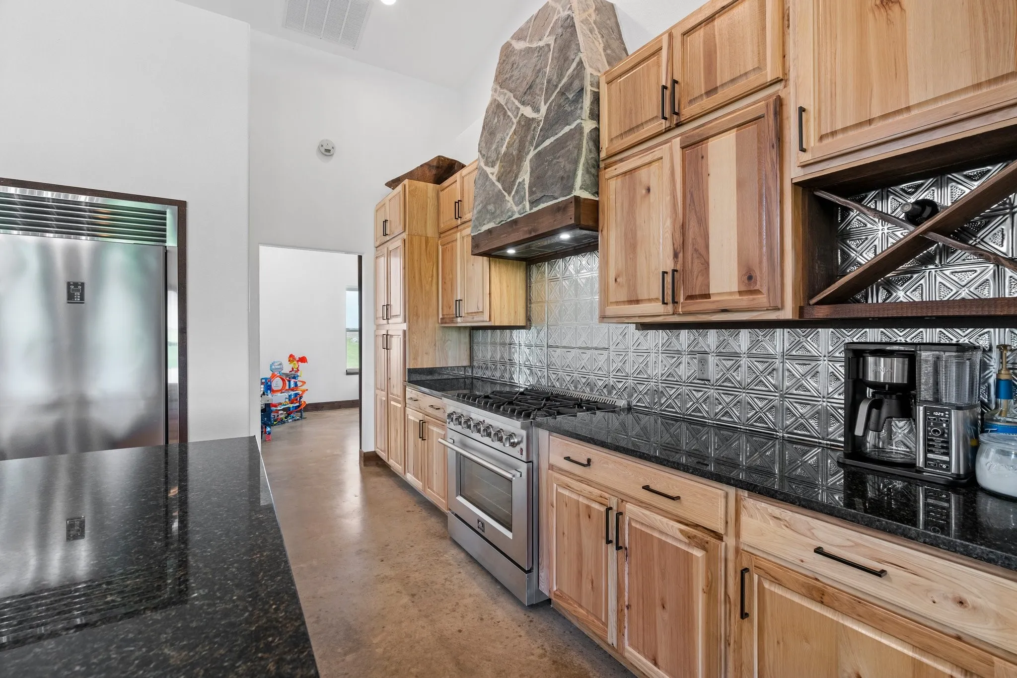 Kitchen featuring dark stone counters, tasteful backsplash, premium appliances, and custom exhaust hood