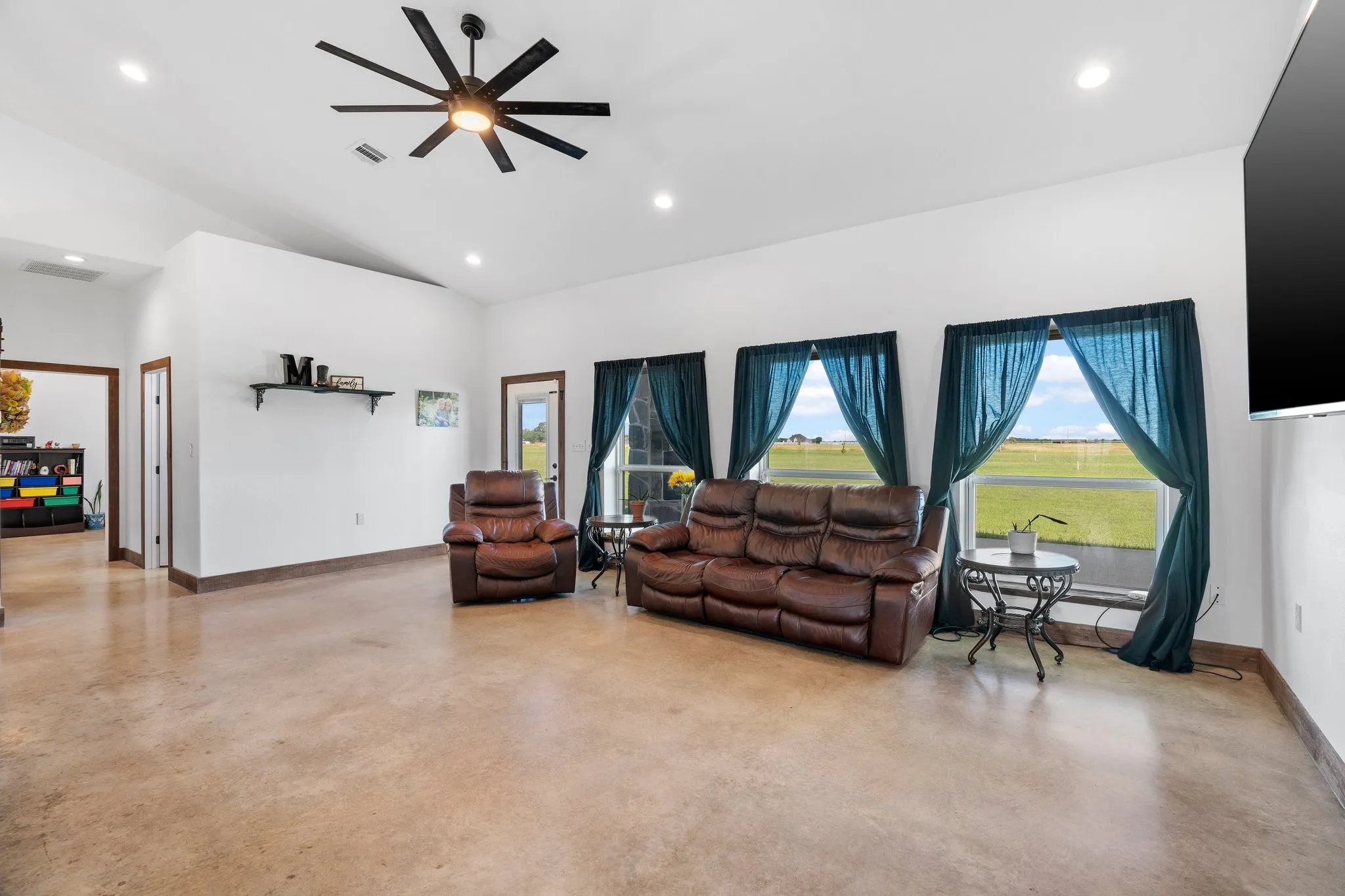 Living room with ceiling fan and lofted ceiling