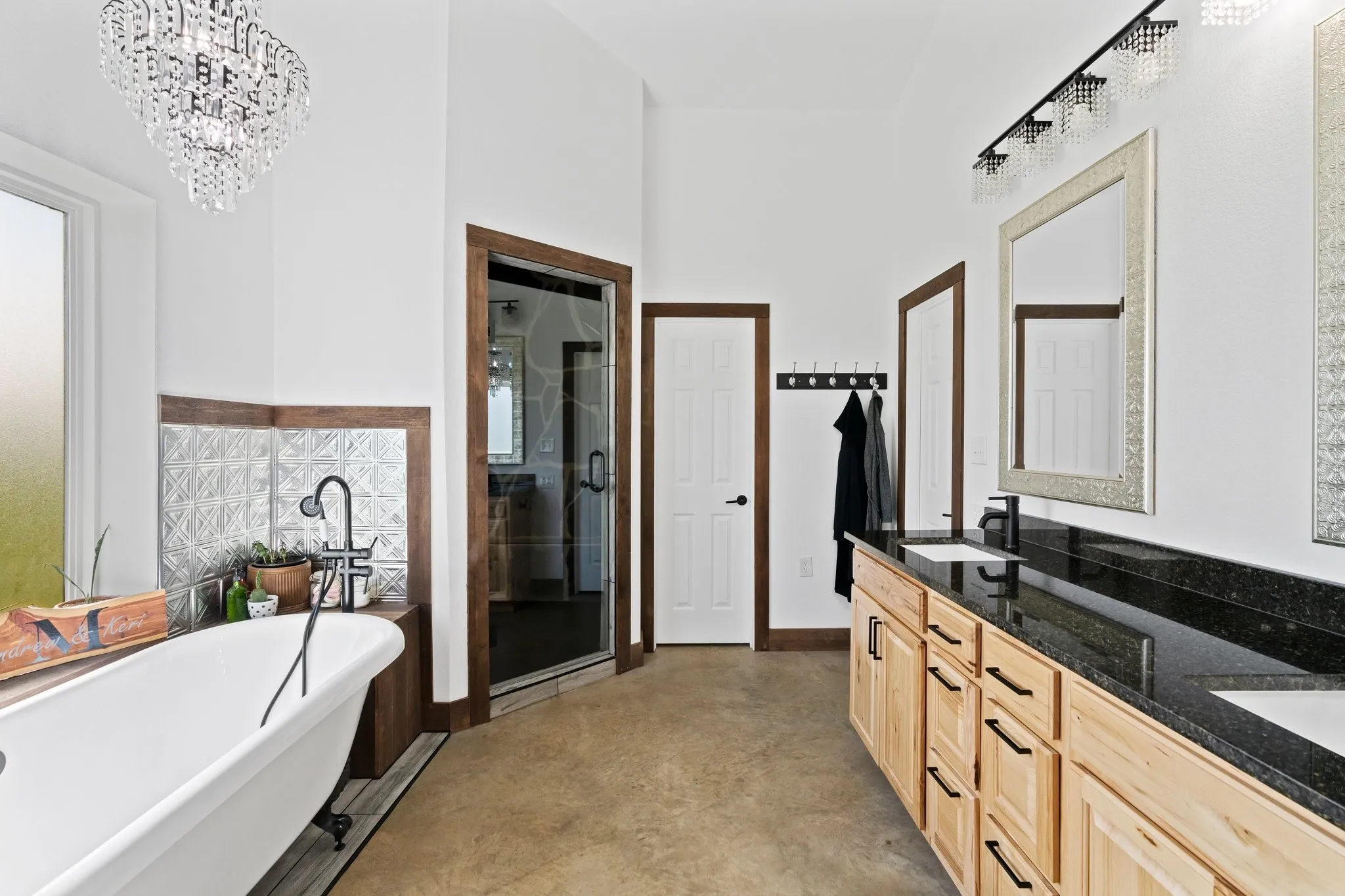 Bathroom featuring a chandelier, concrete flooring, separate shower and tub, and double sink vanity
