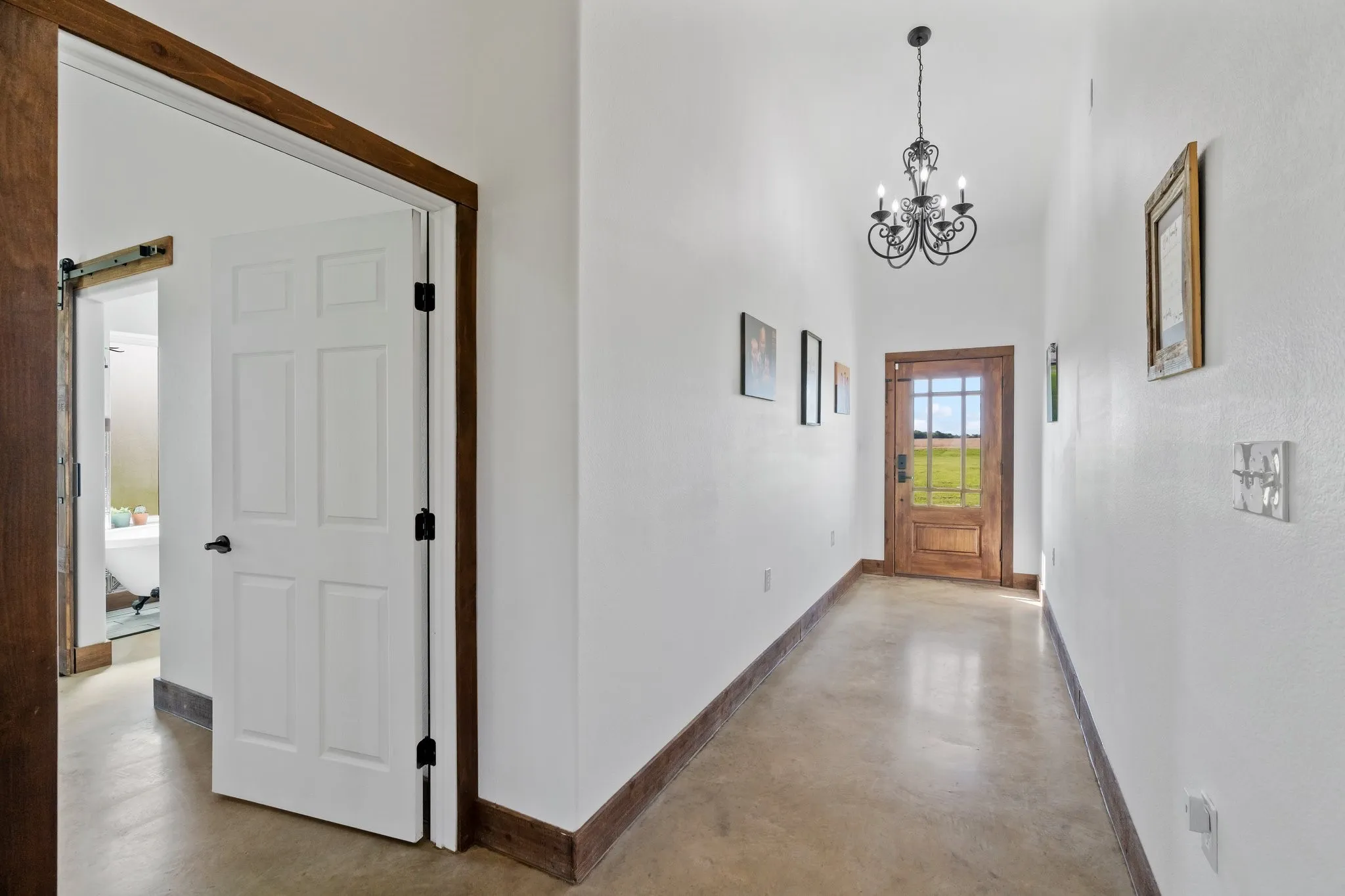 Hall with a barn door, a notable chandelier, a high ceiling, and concrete flooring
