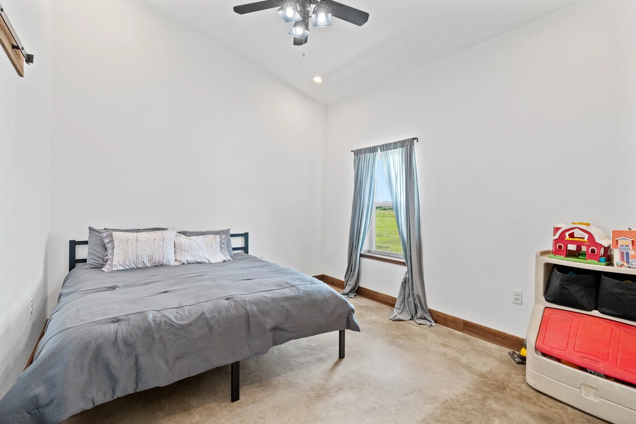 Carpeted bedroom featuring ceiling fan and vaulted ceiling