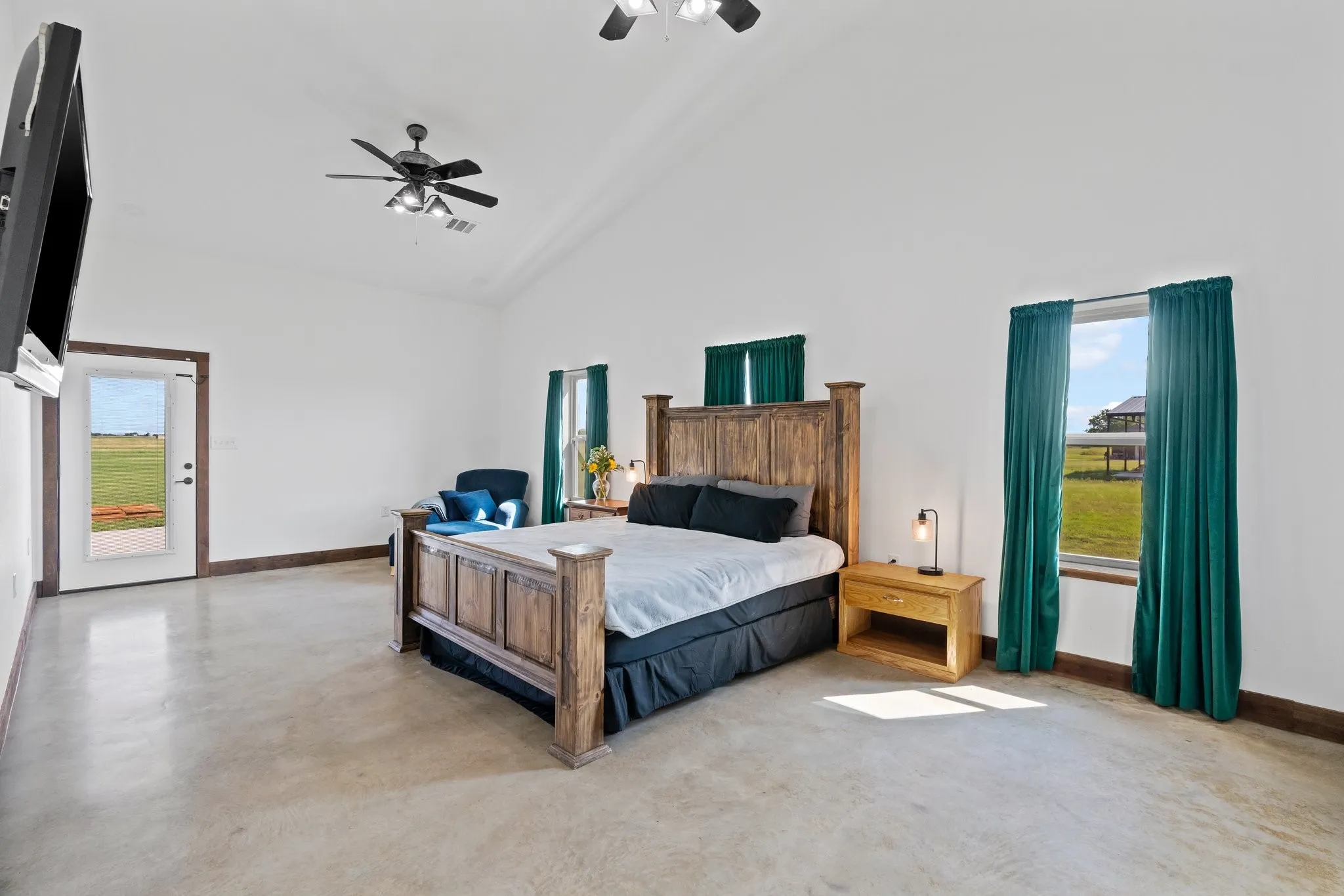 Bedroom with high vaulted ceiling, ceiling fan, concrete flooring, and access to outside