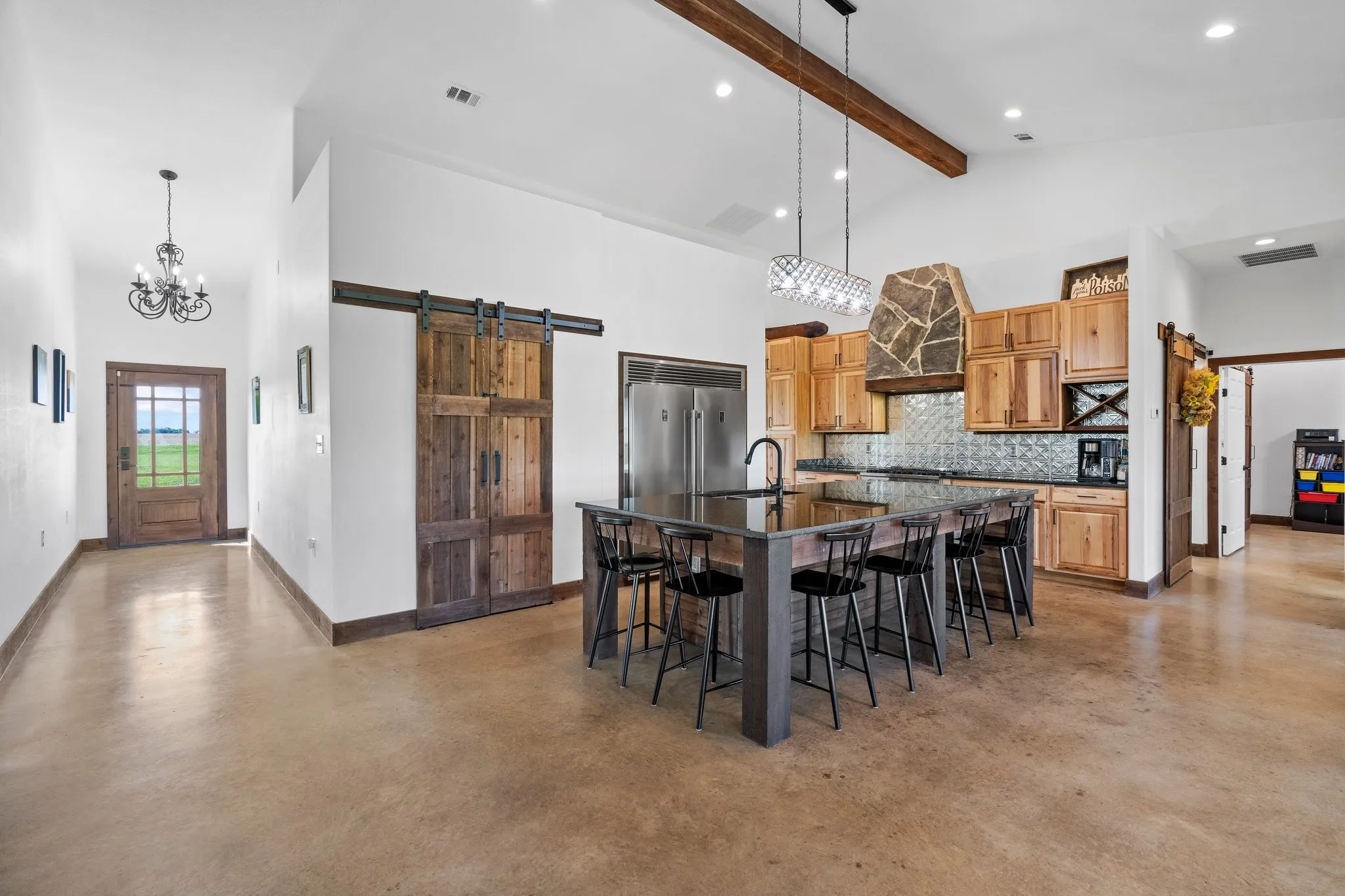 Dining room featuring an inviting chandelier, a barn door, high vaulted ceiling, beamed ceiling, and sink
