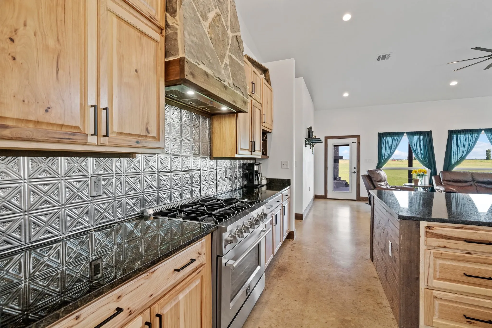 Kitchen with backsplash, custom exhaust hood, range with gas cooktop, and light brown cabinets