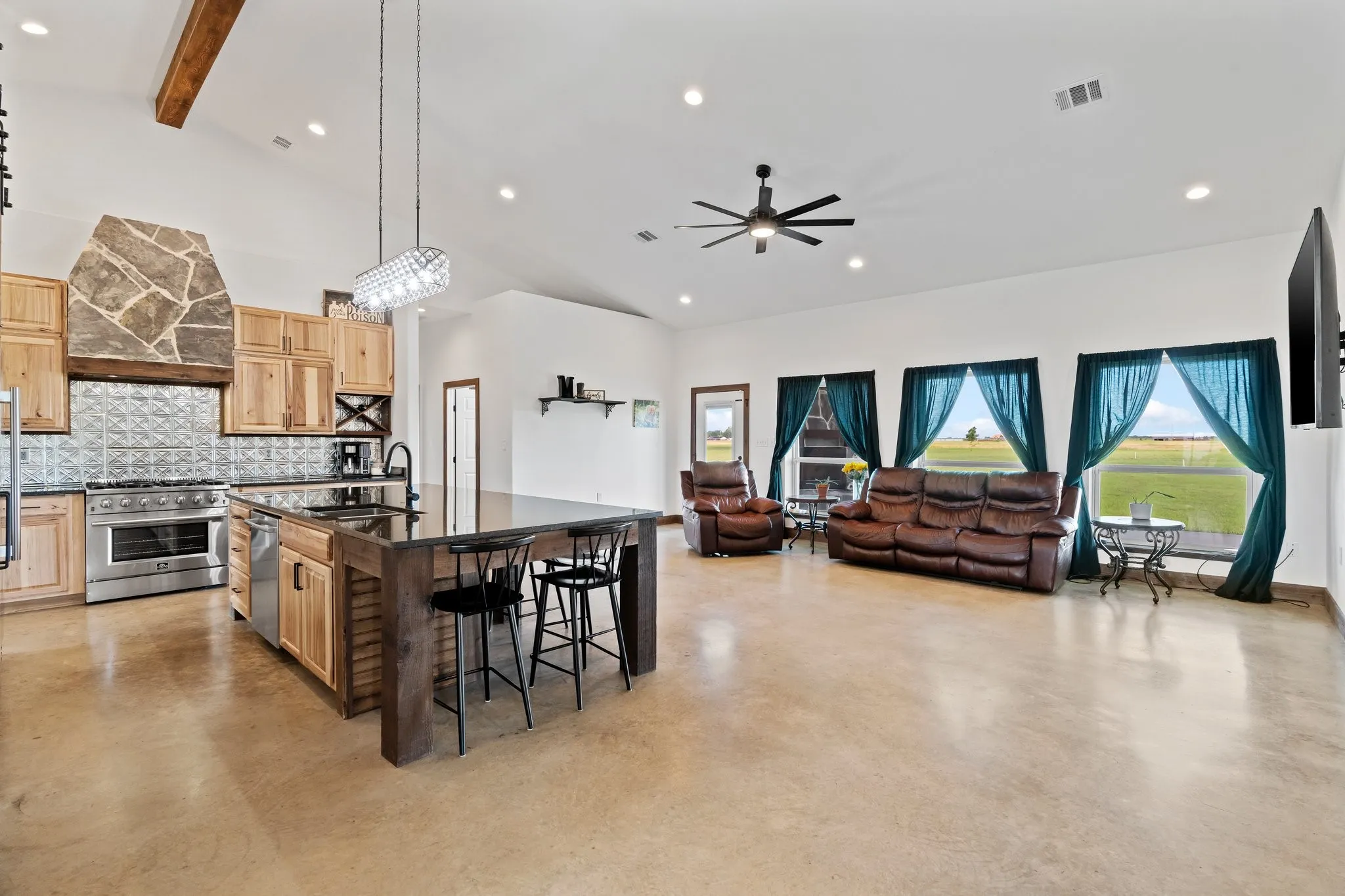Kitchen featuring an island with sink, wall chimney exhaust hood, backsplash, sink, and appliances with stainless steel finishes