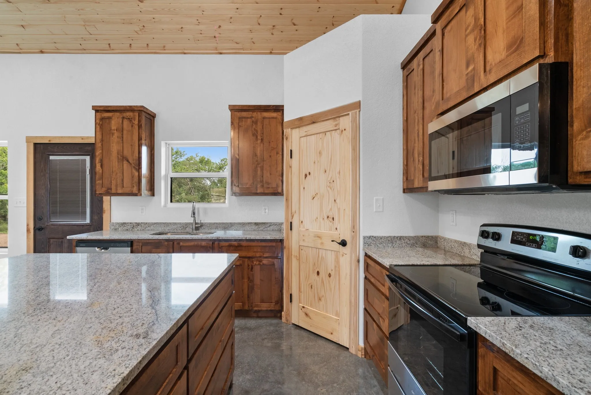 Kitchen featuring wooden ceiling, appliances with stainless steel finishes, sink, and light stone countertops