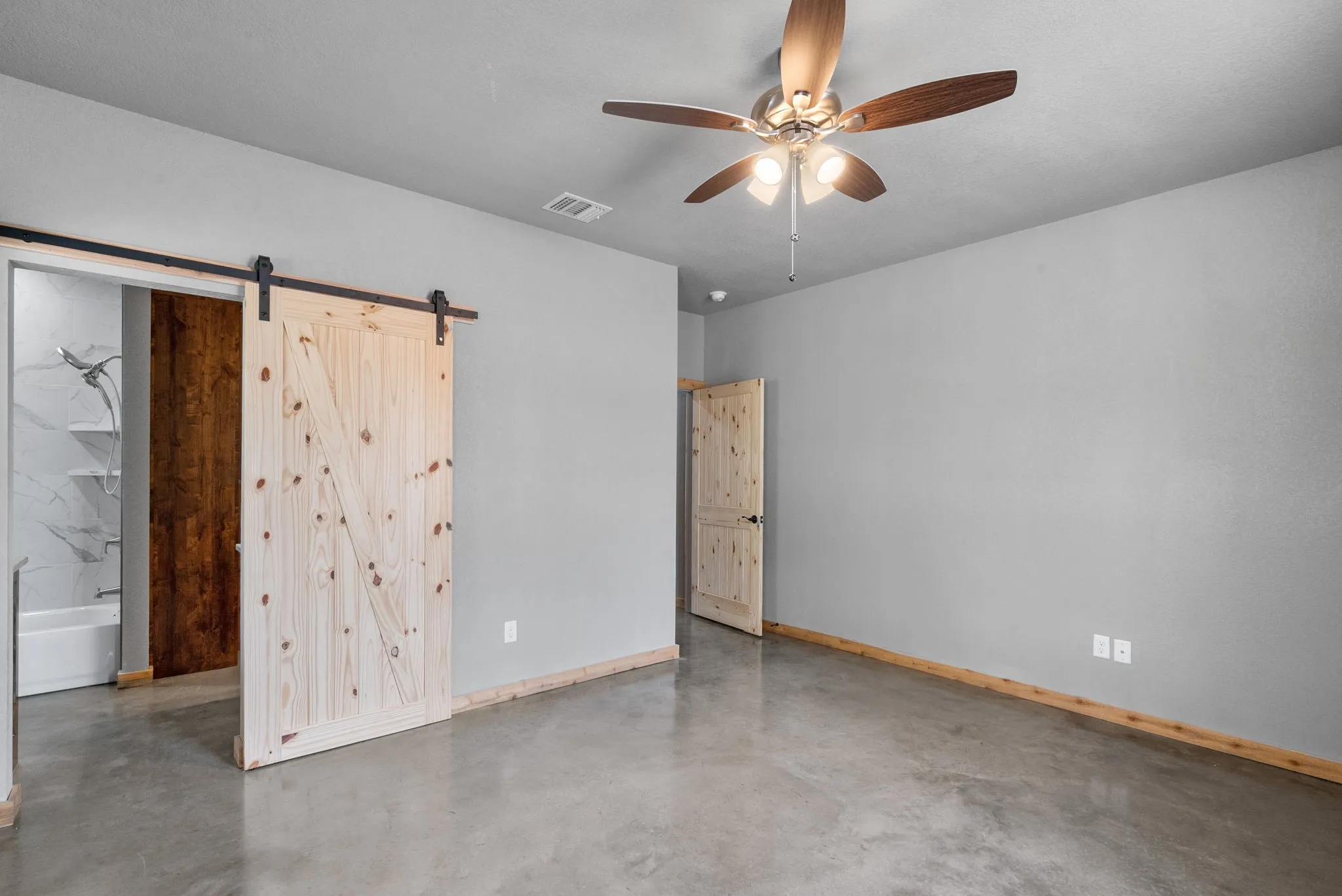 Spare room with a barn door and ceiling fan
