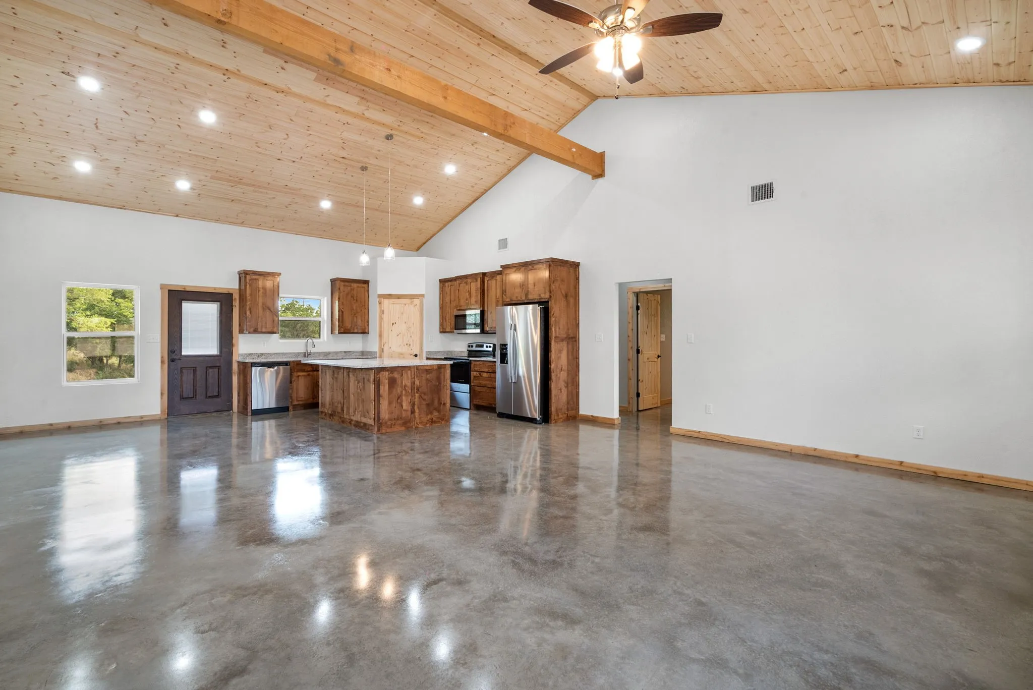 Unfurnished living room with high vaulted ceiling, beam ceiling, sink, and ceiling fan